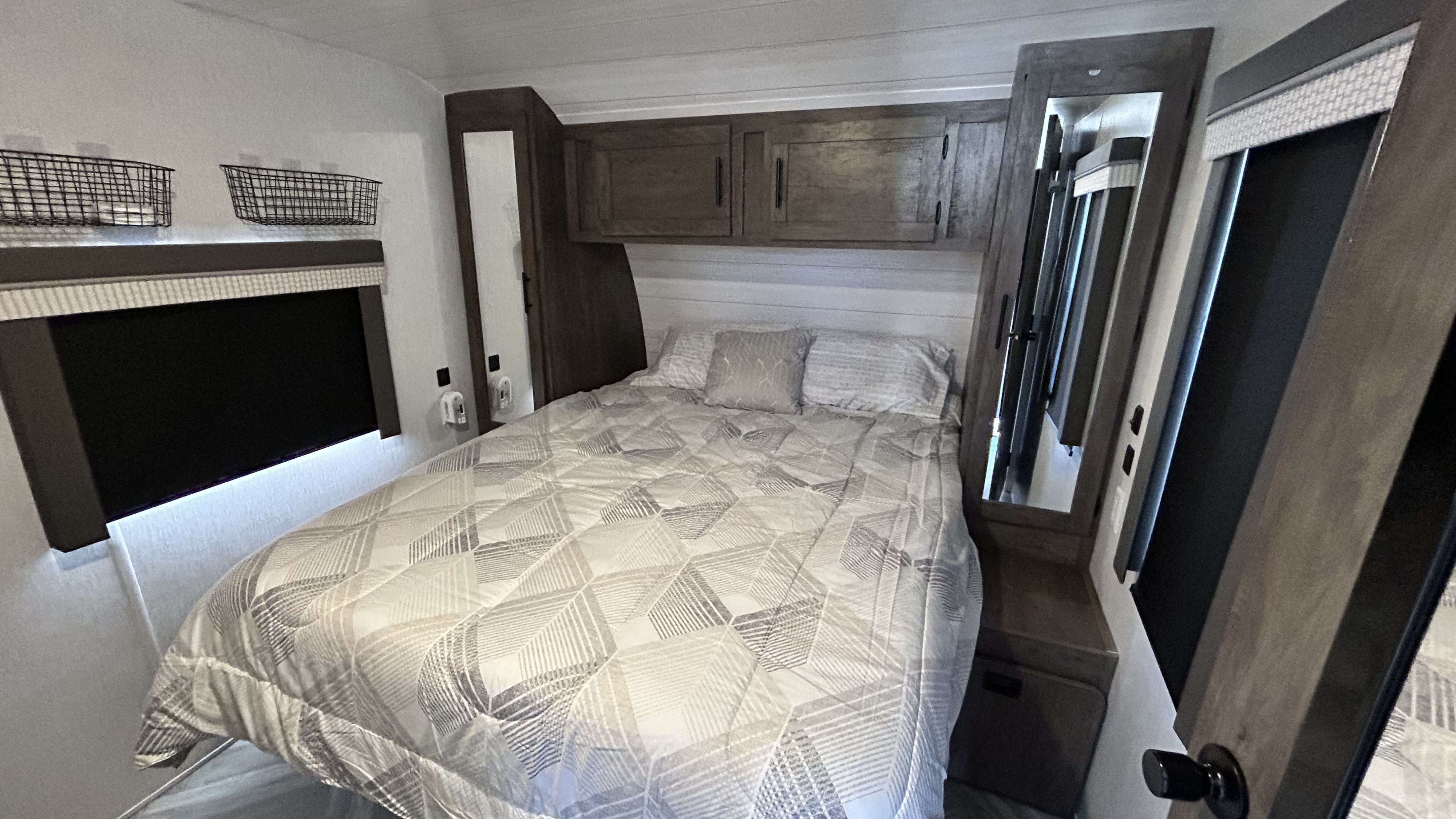 Comfortable RV rental bedroom featuring a full bed, overhead storage, and modern design. Ideal for your next adventure.. Forest River Wildwood 2022