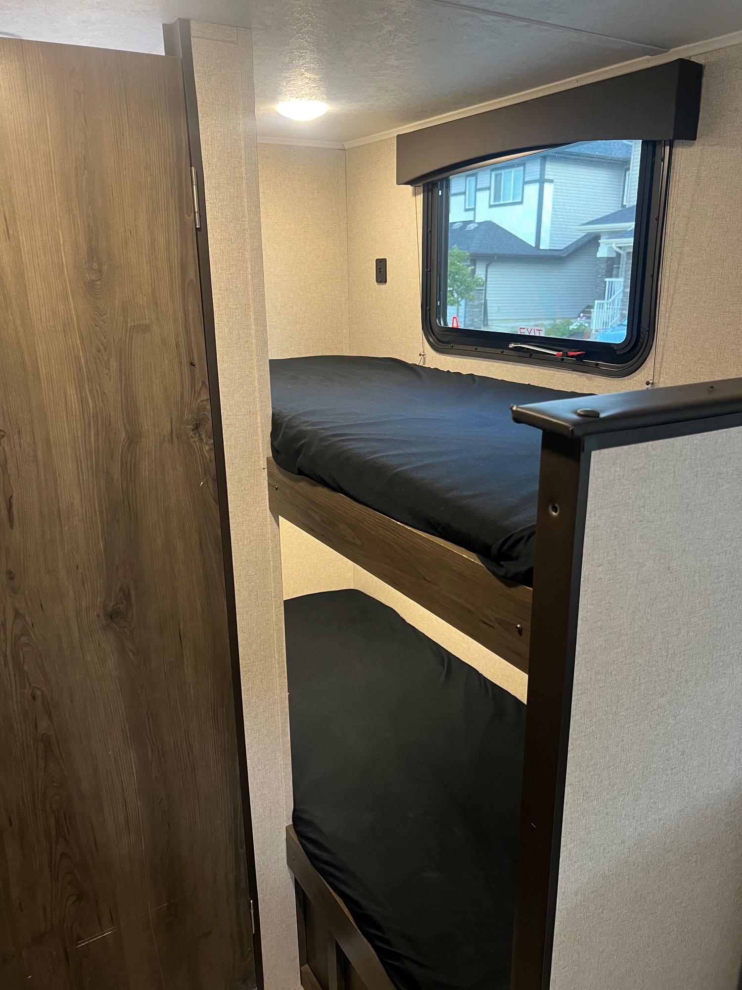 RV rental bunk beds: A cozy sleeping area with a window view of houses, ideal for your next travel adventure.. Viking 1706 2021