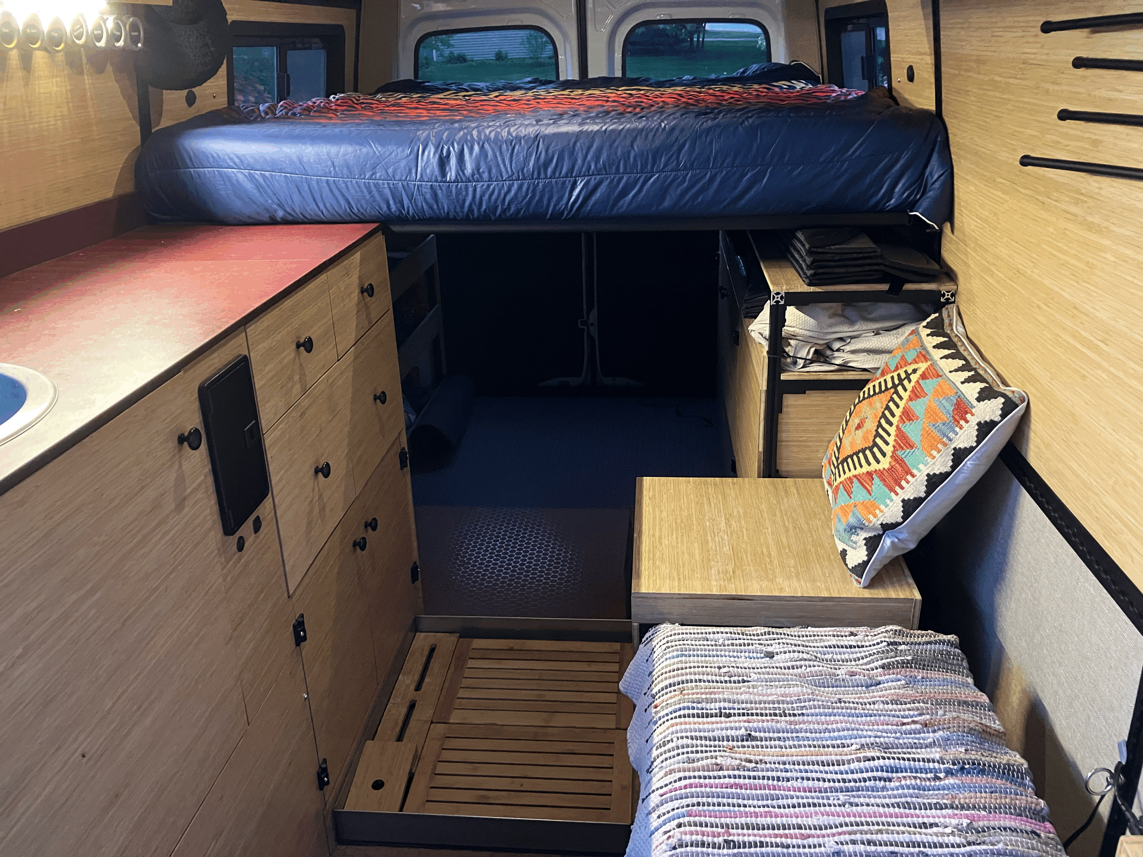RV rental: Inside a custom camper van with an elevated bed, kitchen counter, and clever storage solutions.. Mercedes Sprinter 2020