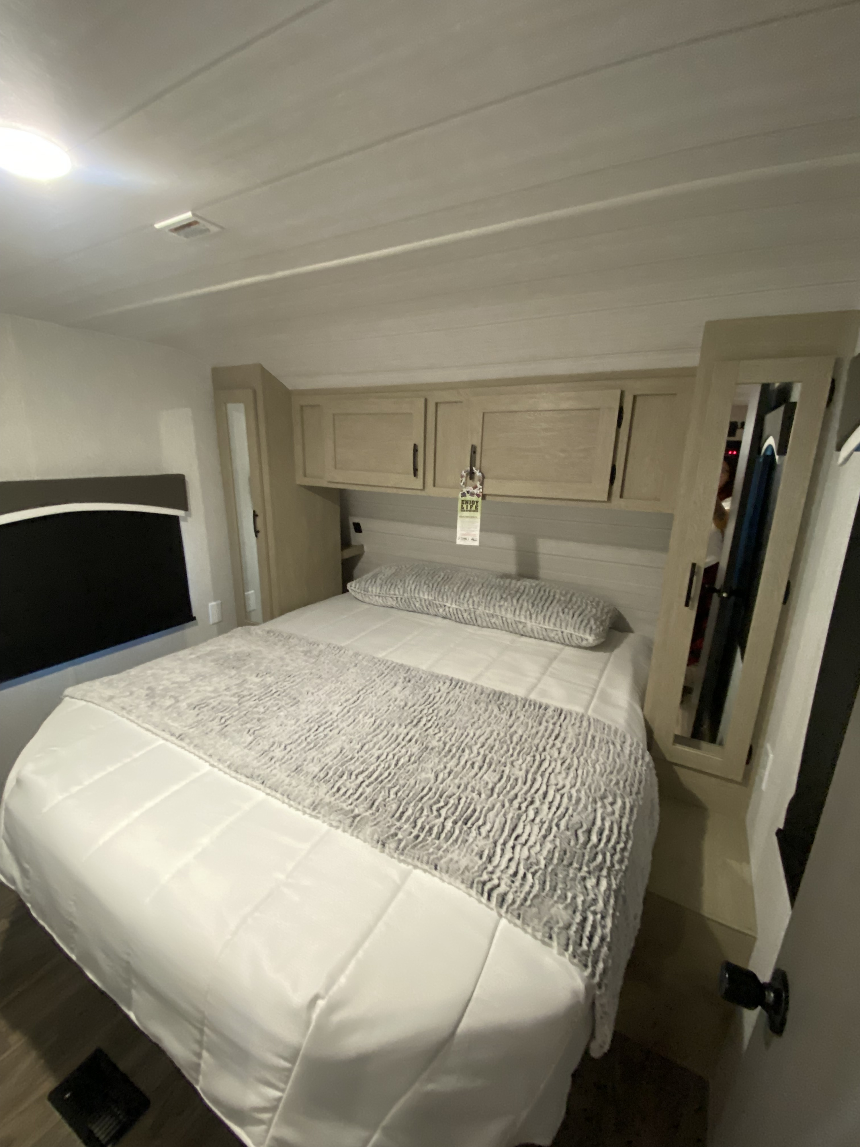 Experience comfort in this RV rental bedroom with a neatly made bed, overhead cabinets, and reflective closet doors.. Forest River EVO 2023