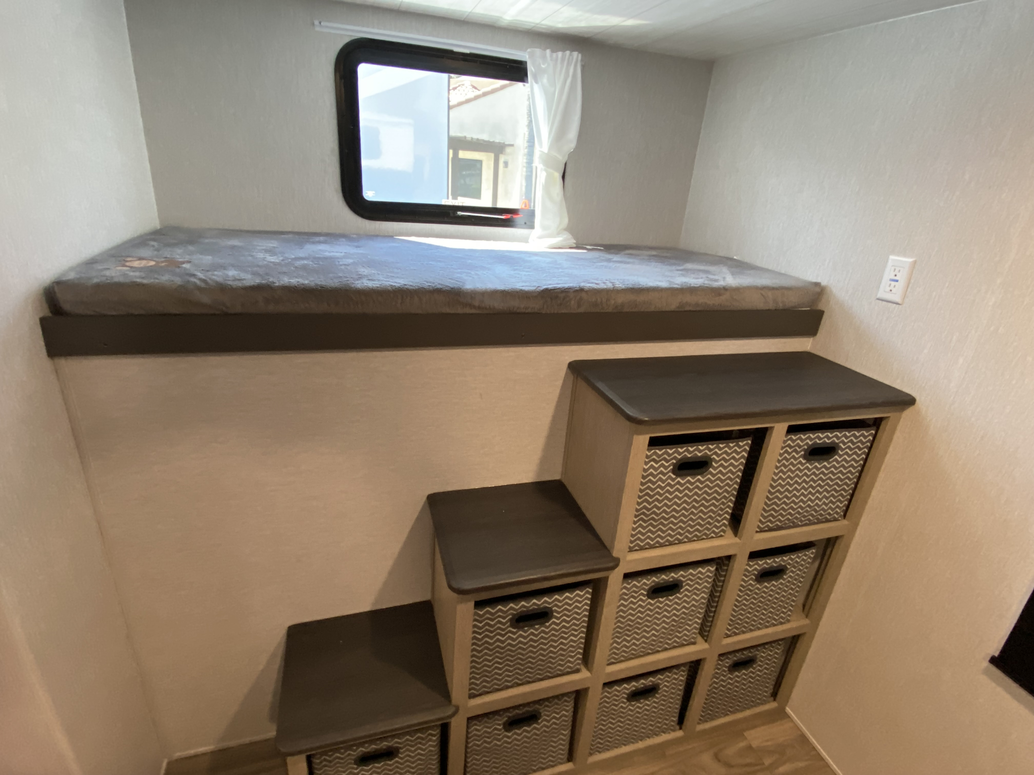 RV rental bunk bed, clever storage stairs with patterned bins. Bright interior for your adventures.. Forest River EVO 2023