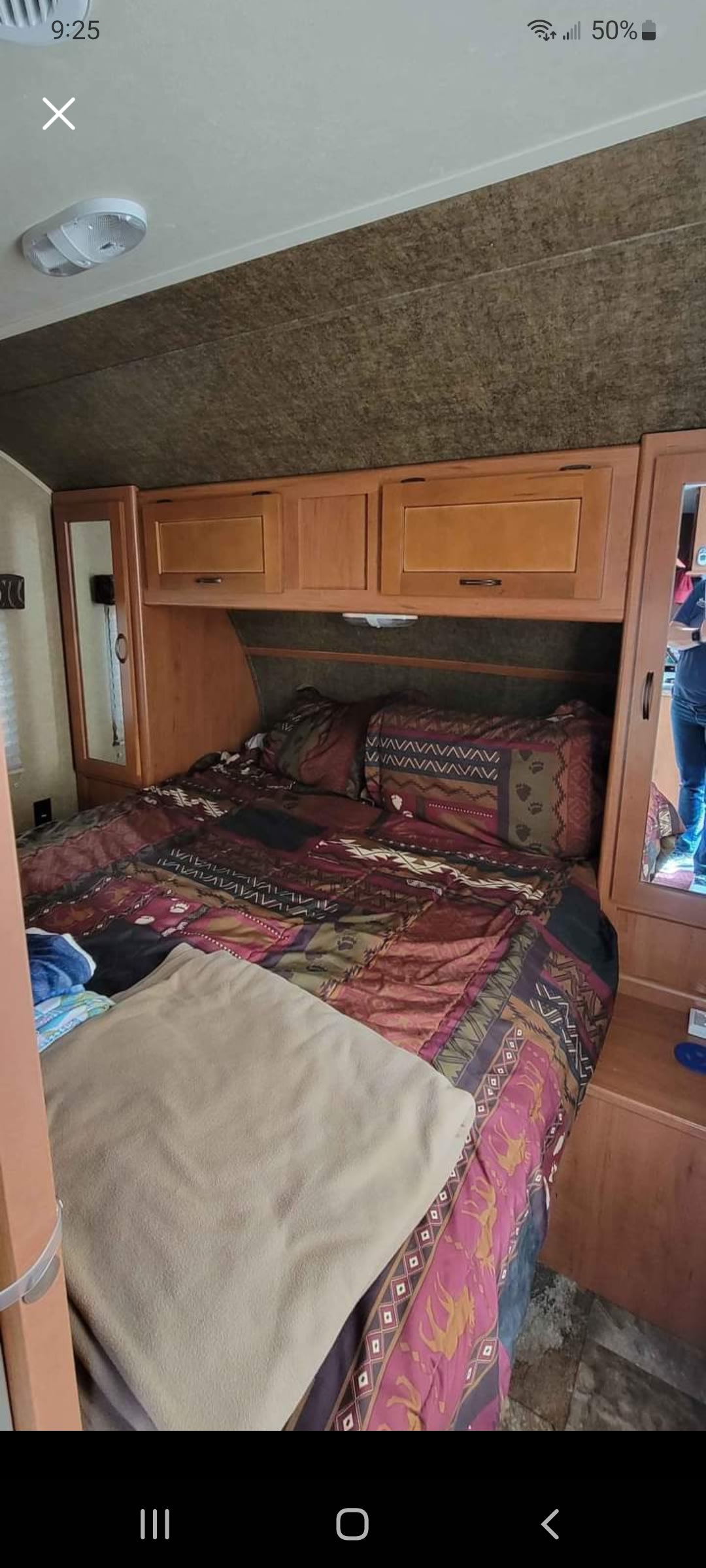 RV rental bedroom showcasing comfortable bed with patterned bedding, storage cabinets, and side mirrors.. Forest River Cherokee Grey Wolf 2015