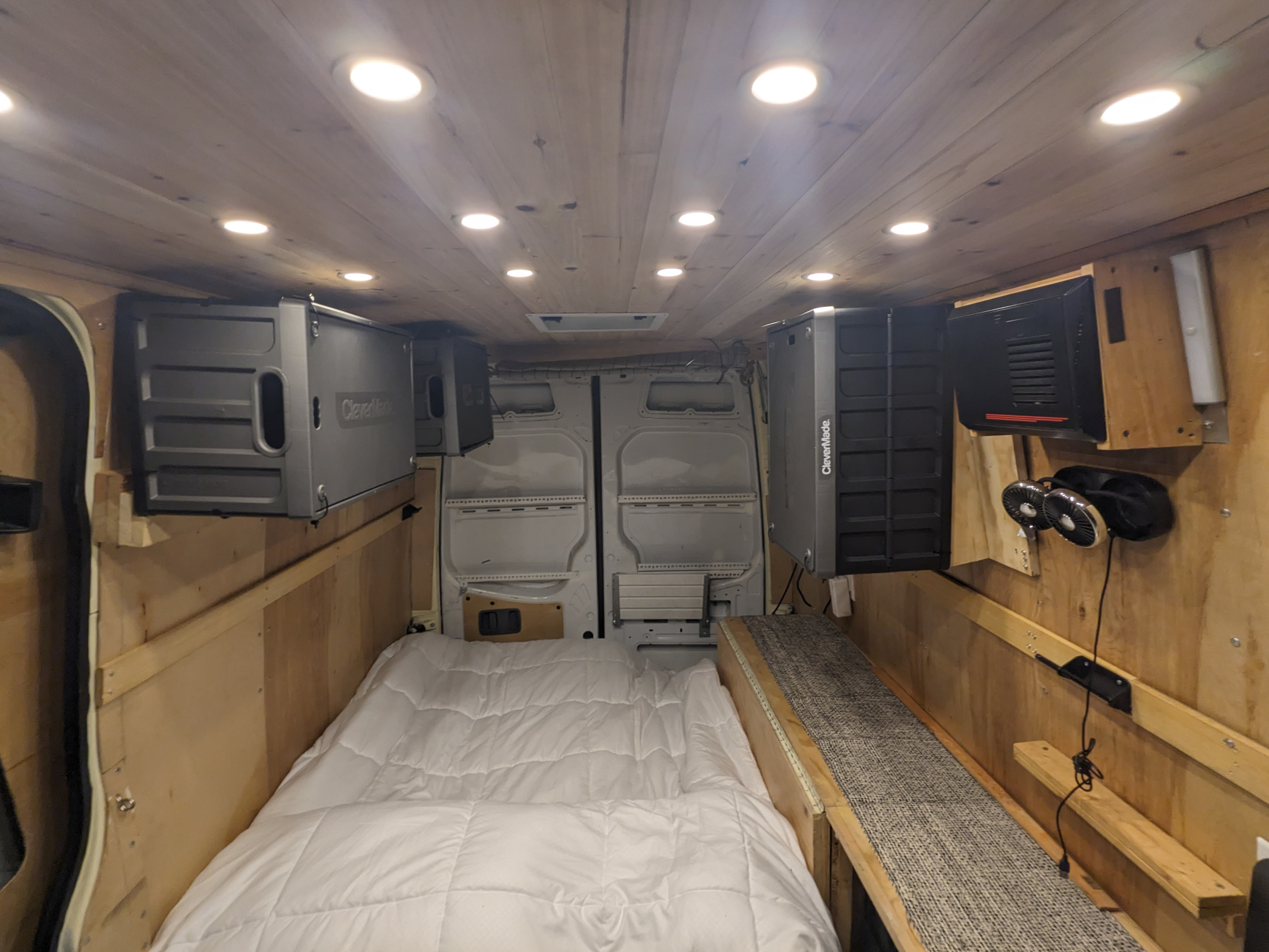 Inside a custom RV rental camper van: wood ceiling with lights, comfy bed, wall-mounted storage, and fans. Ready for adventure!. Mercedes Benz Sprinter 2500 2014
