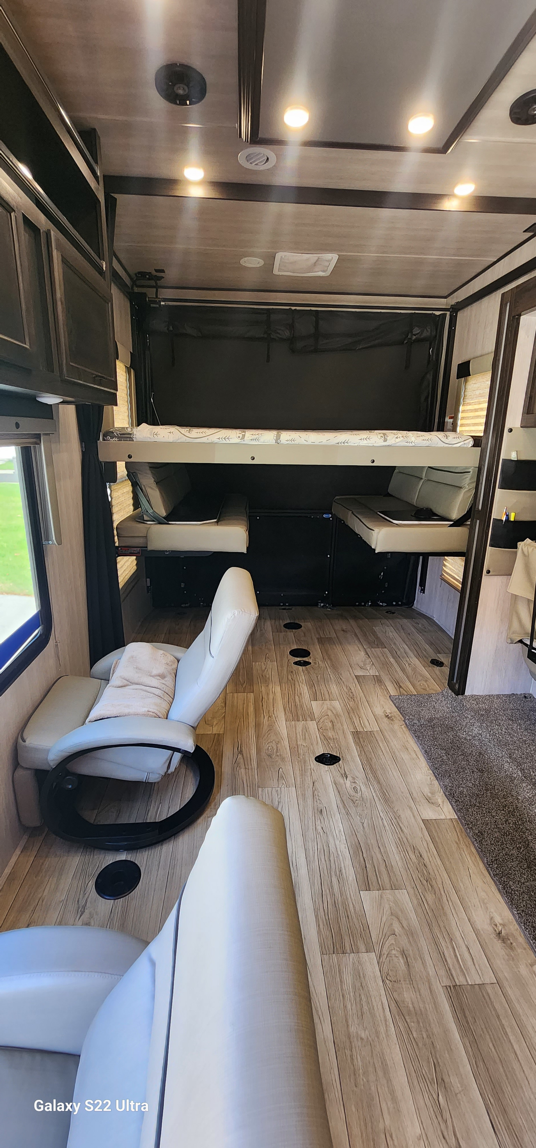 Explore this RV rental's adaptable interior: a toy hauler with raised bunk bed, fold-up benches, and recliners.. Genesis Supreme Rv RAGE'N 2815T Fifth Wheel 2023