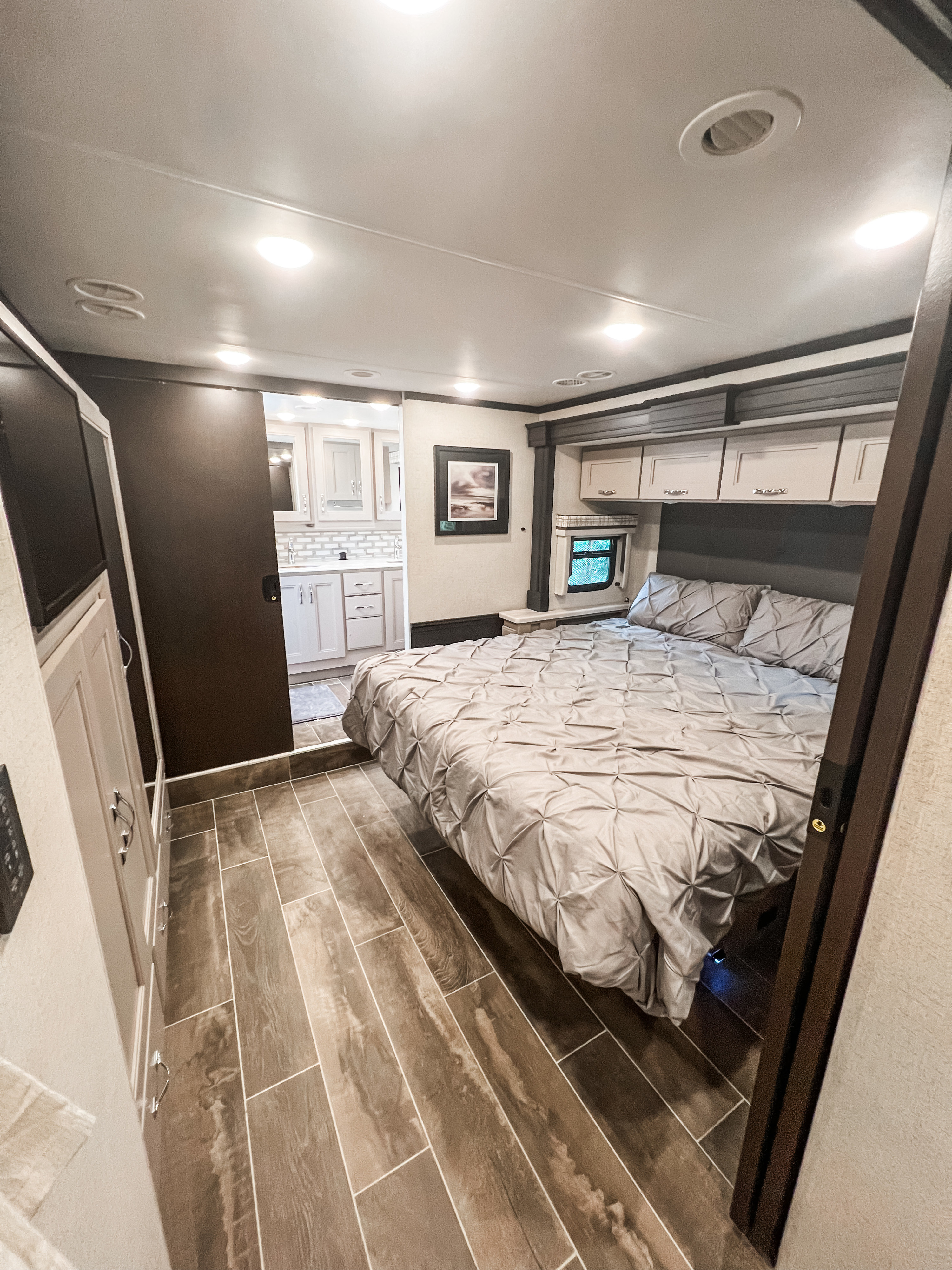 Experience comfort in this RV rental's spacious bedroom, featuring a large bed, overhead storage, and a modern attached bathroom.. Thor Aria 2024
