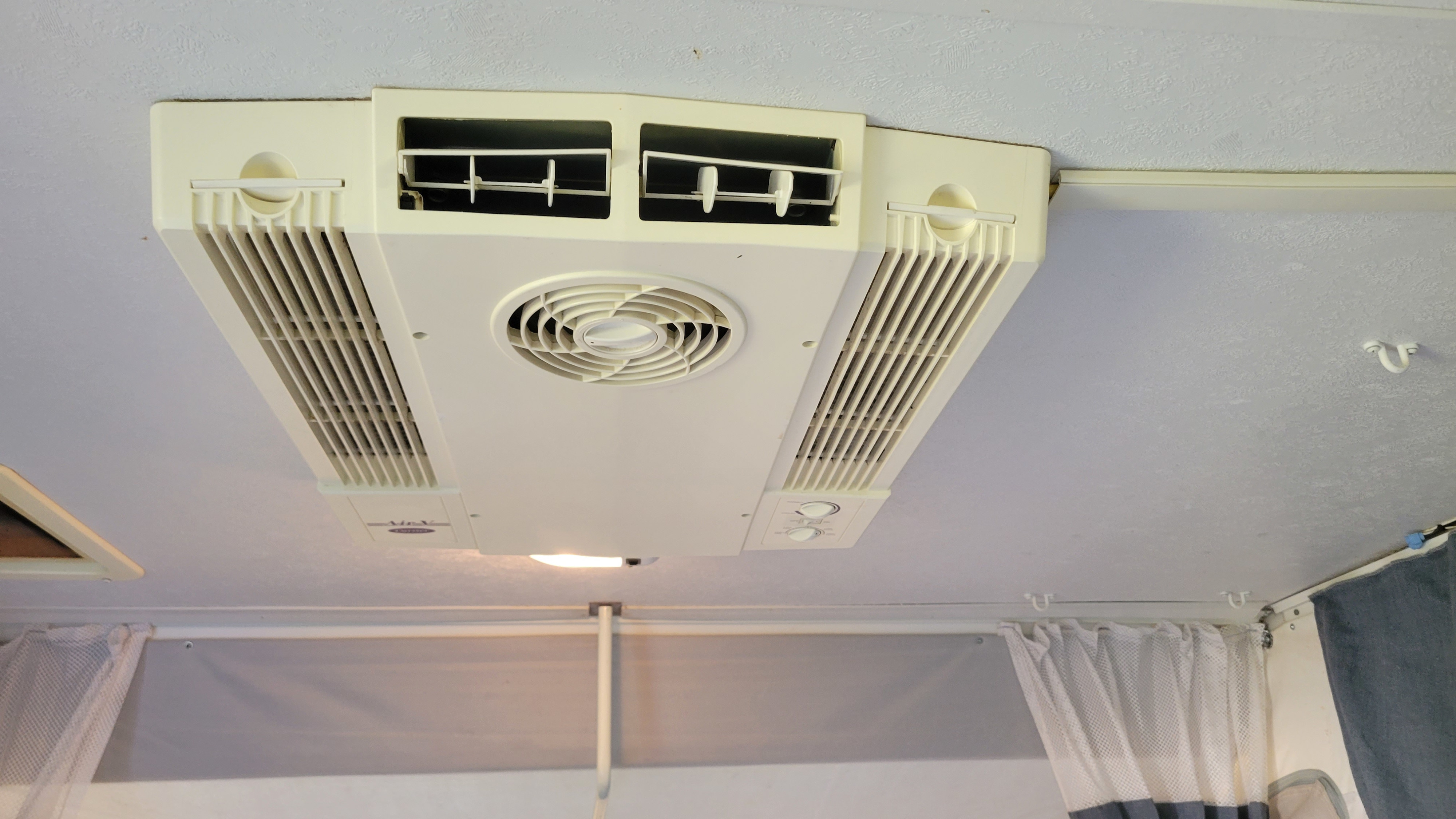 Ceiling view of an RV rental with a central air conditioning unit, featuring vents, fan, light, and controls for comfort.. Palomino Pony pop-up 2009