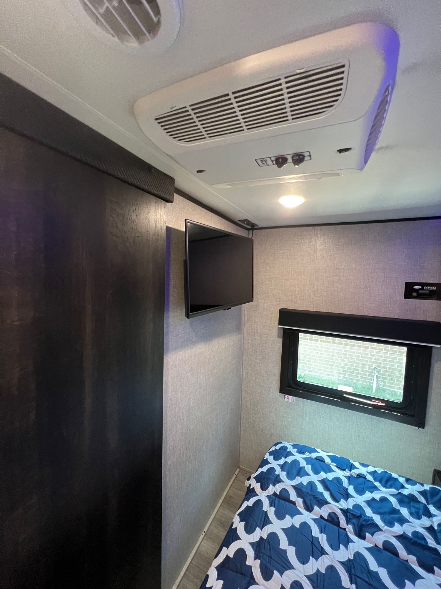 Experience a comfortable RV rental bedroom, featuring a patterned bed, wall-mounted TV, and ceiling AC, perfect for your travels.. Jayco Jay Flight SLX 2022