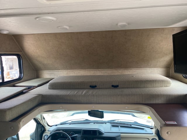 Spacious RV rental cab-over bunk bed with a comfortable mattress, side cushions, TV, and large window.. Forest River Sunseeker 2016