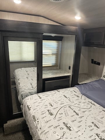 RV rental bunk room: A cozy interior with two beds, one seen in the mirrored closet door.. Genesis Supreme Rv RAGE'N 2815T Fifth Wheel 2023