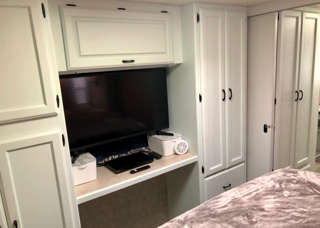 Modern RV rental interior showcasing bright white cabinets with black hardware, a TV, and functional desk space.. Holiday Rambler Admiral SE 2004