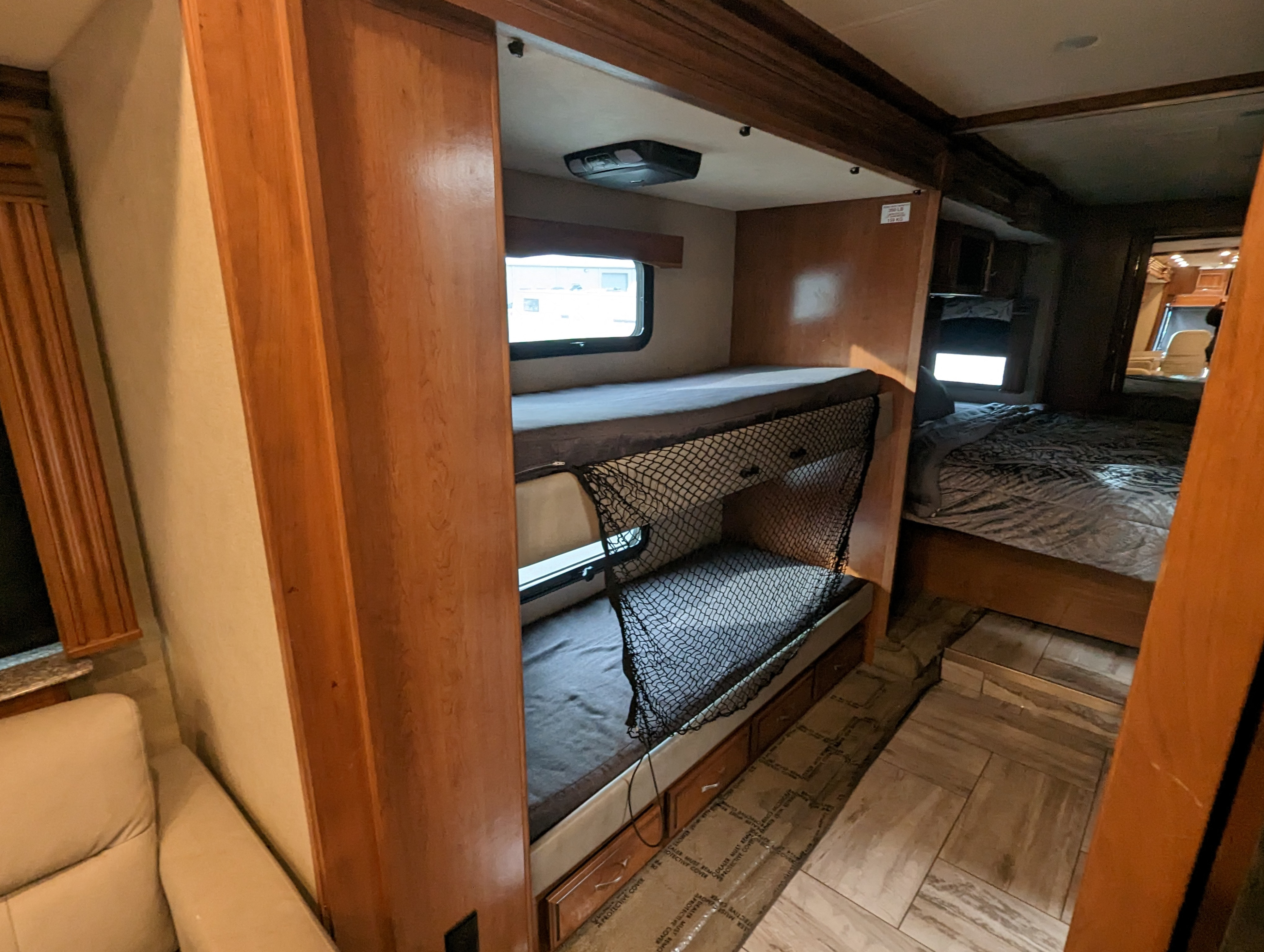 Spacious RV rental interior featuring stacked bunk beds with a safety net and a cozy master bed beyond. Perfect for family trips.. Fleetwood Discovery 2017