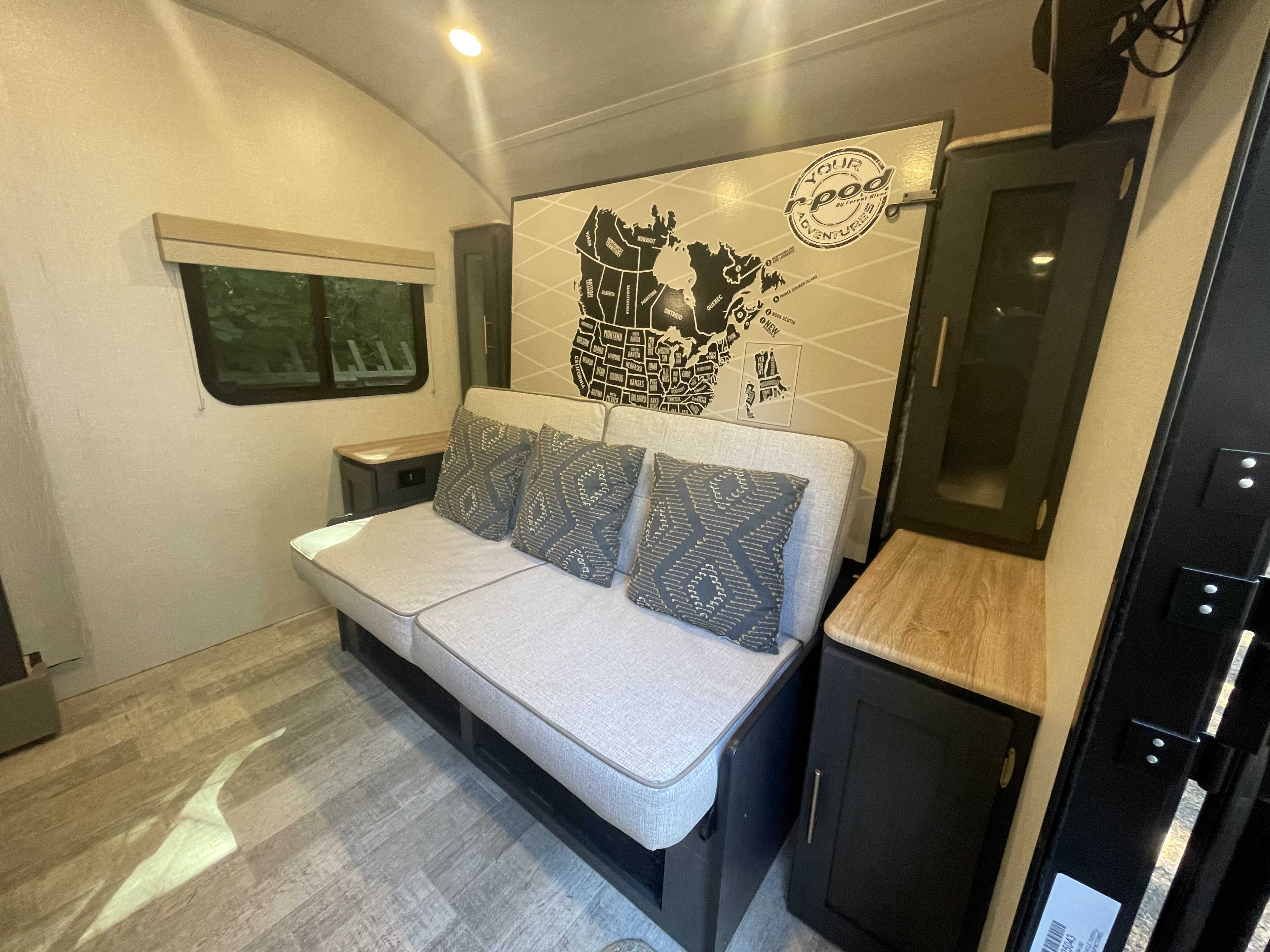 RV rental interior: A light gray couch with pillows, a large map mural of North America, and dark cabinetry. Ready for your adventures!. Forest River Rpod 203 Beast Mode 2023