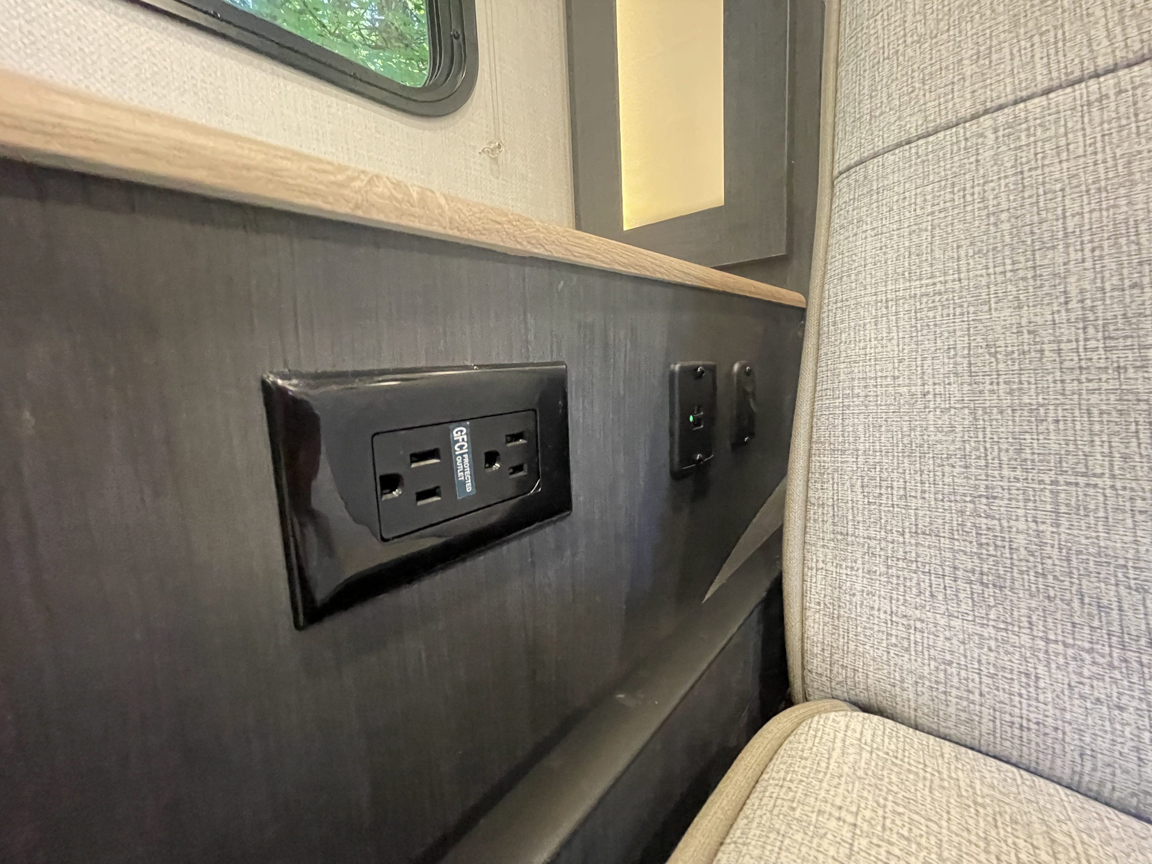 RV rental interior detail: a GFCI outlet, illuminated USB ports, and textured fabric seating for passenger convenience.. Forest River Rpod 203 Beast Mode 2023
