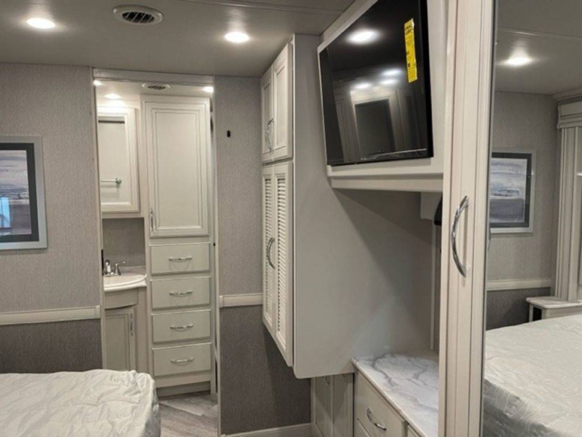 Explore this RV rental's bedroom, featuring a mounted TV, integrated vanity with sink, and ample built-in storage.. Fleetwood Other 2022