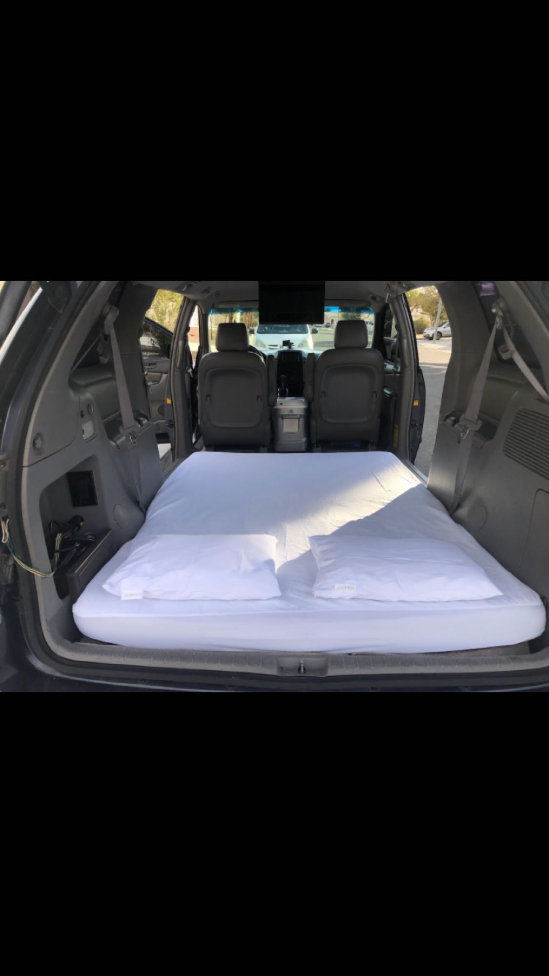 This image shows a white mattress and pillows inside a vehicle, creating a cozy bed for car camping. It's like a compact RV rental experience.. Other Other 2009