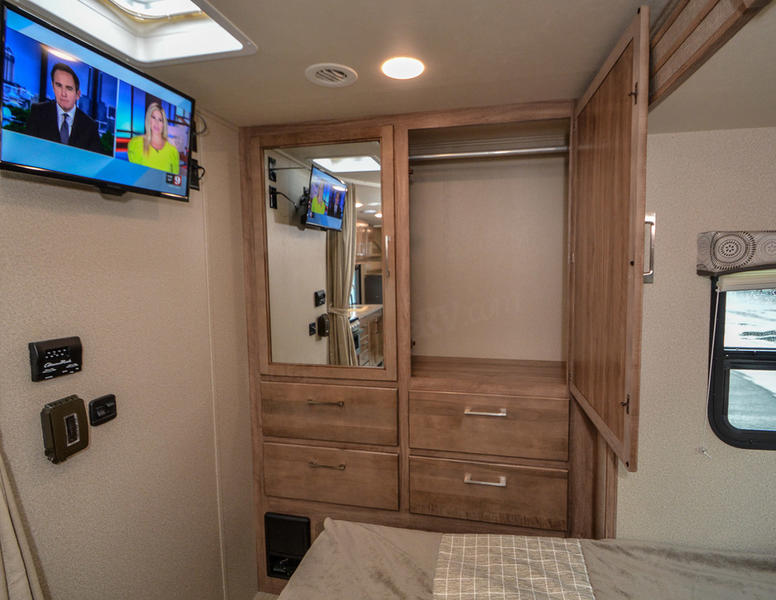 RV rental bedroom with TV, mirrored wardrobe, and storage drawers. Cozy interior perfect for your next adventure.. Entegra Coach Odyssey 2020