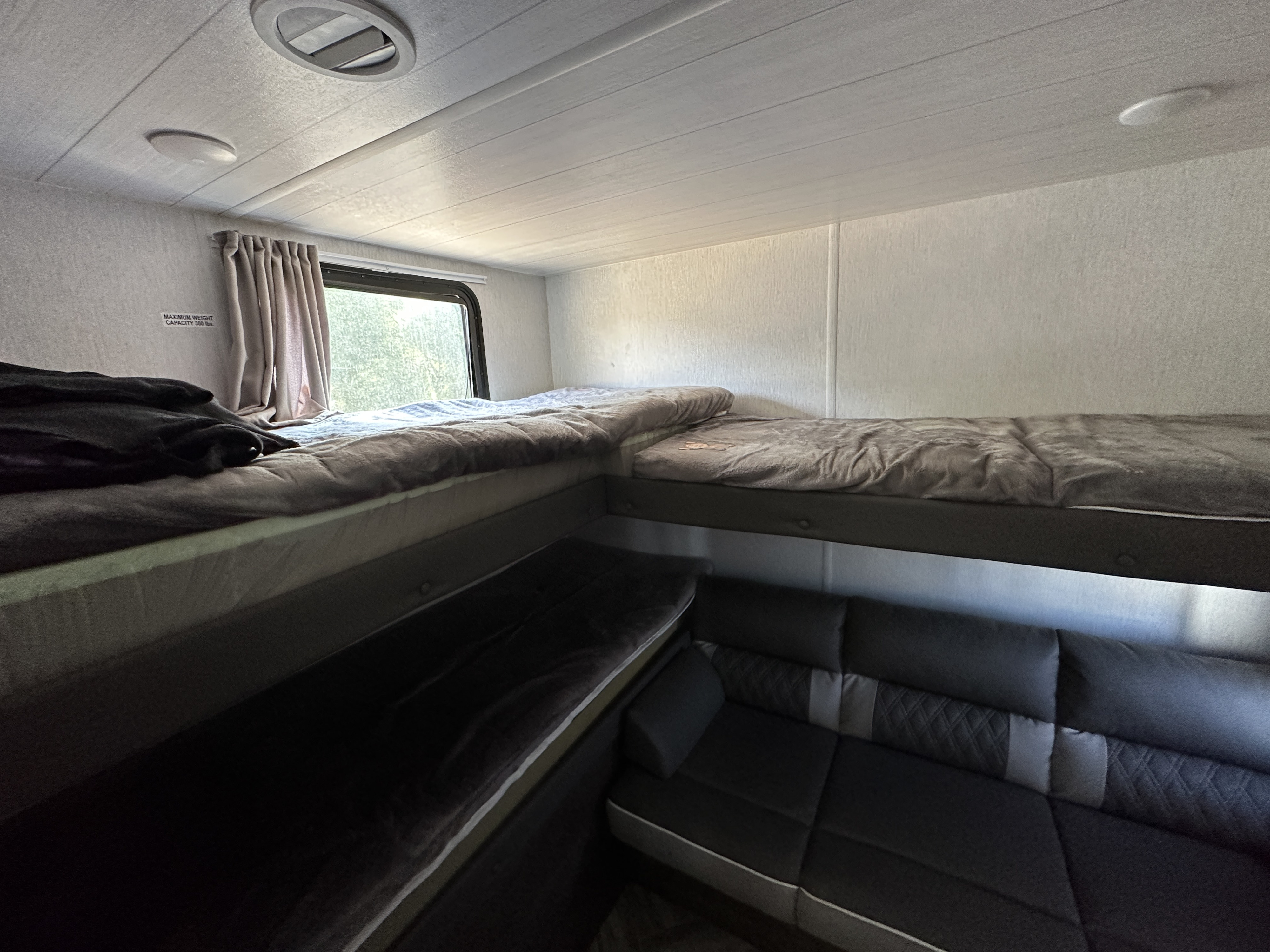 RV rental interior: multiple comfortable bunk beds and a sofa seating area offer versatile living space.. Forest River Wildwood X-Lite 2022