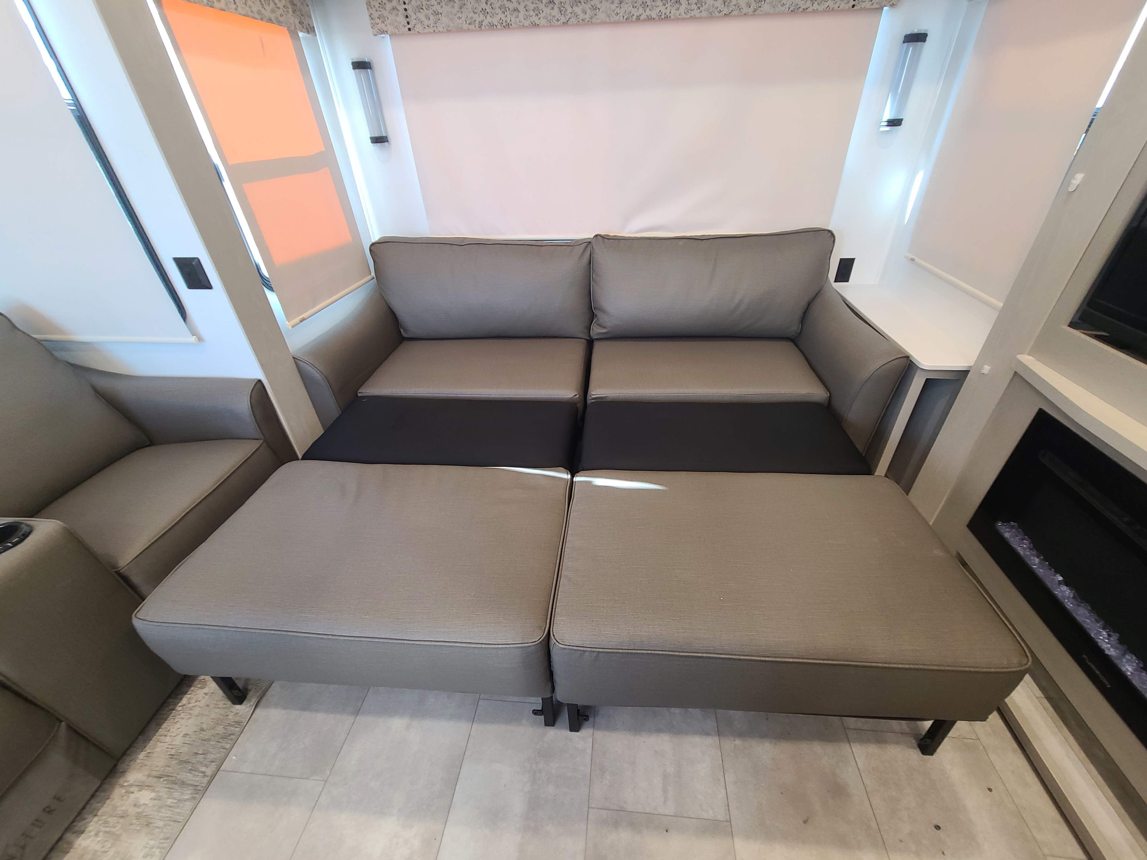Comfortable RV rental interior: A grey modular sofa is extended to a bed. Features modern lighting & fireplace.. Palomino Columbus 2022