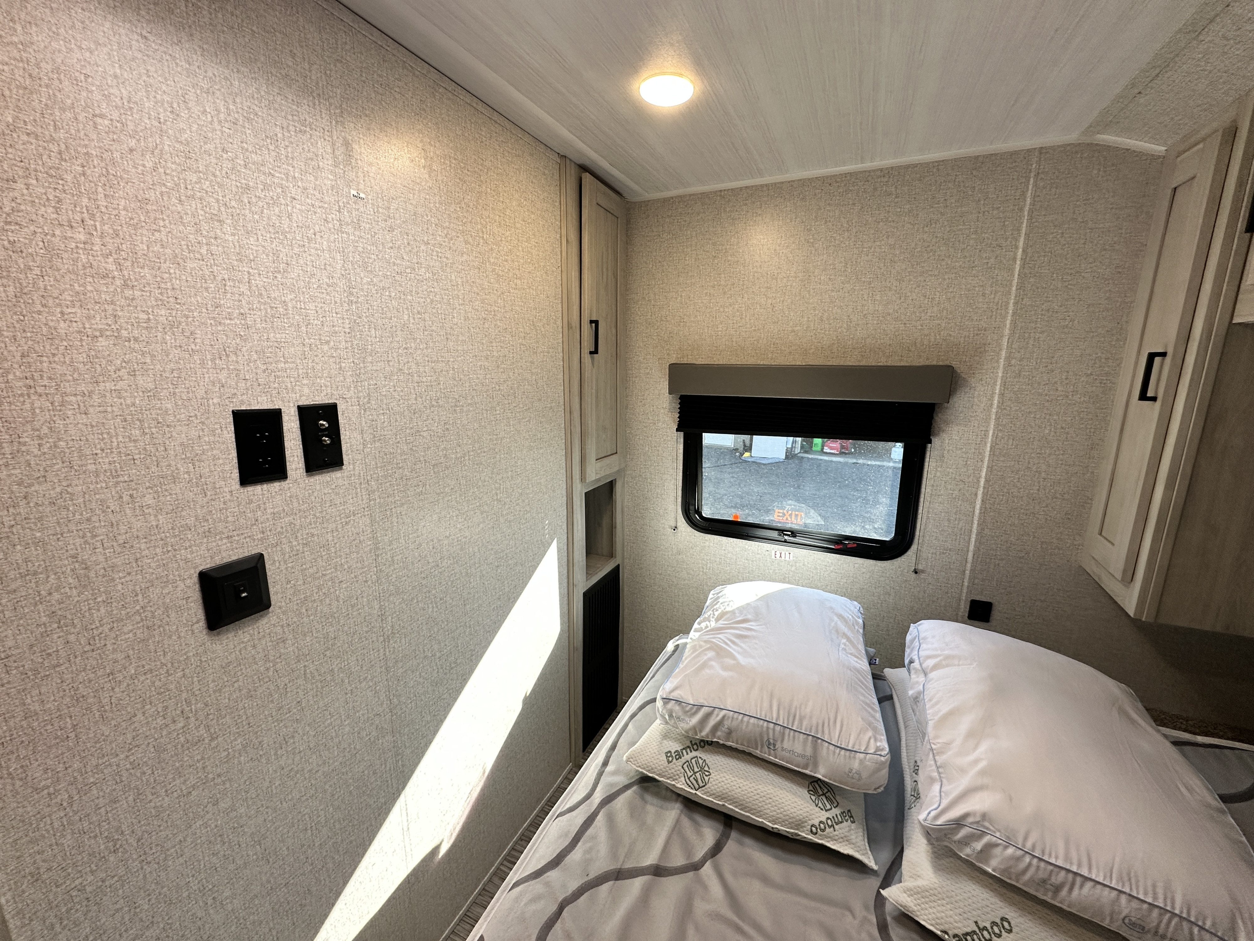 RV rental bedroom: light walls, bed with Serta pillows, window, electrical outlets, and a TV backer. A cozy sleeping space.. Forest River Silver Lake 2023