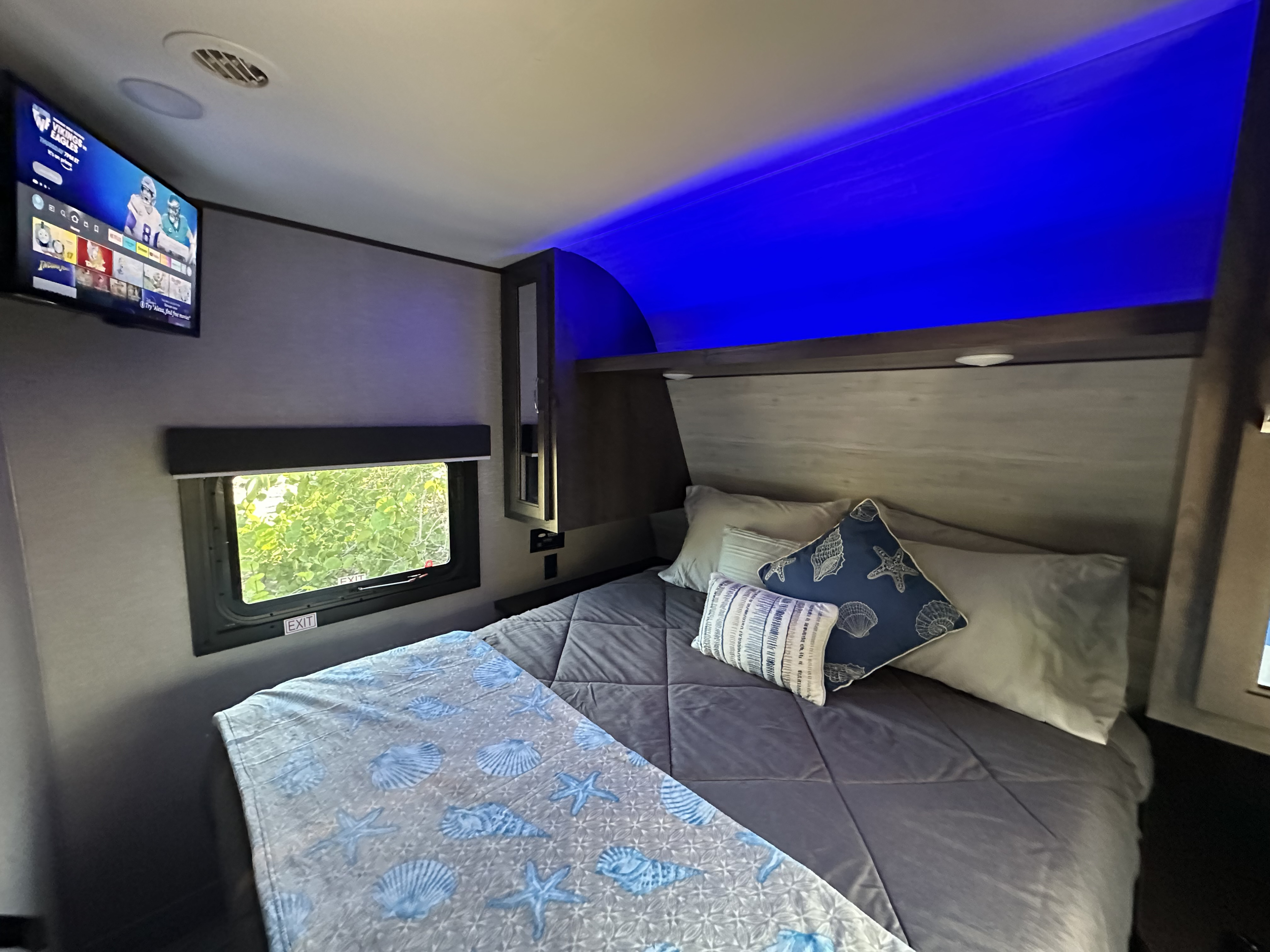 Modern RV rental bedroom with comfy bed, TV, emergency exit window, and cool blue ambient lighting.. Jayco Jay Flight SLX 2020