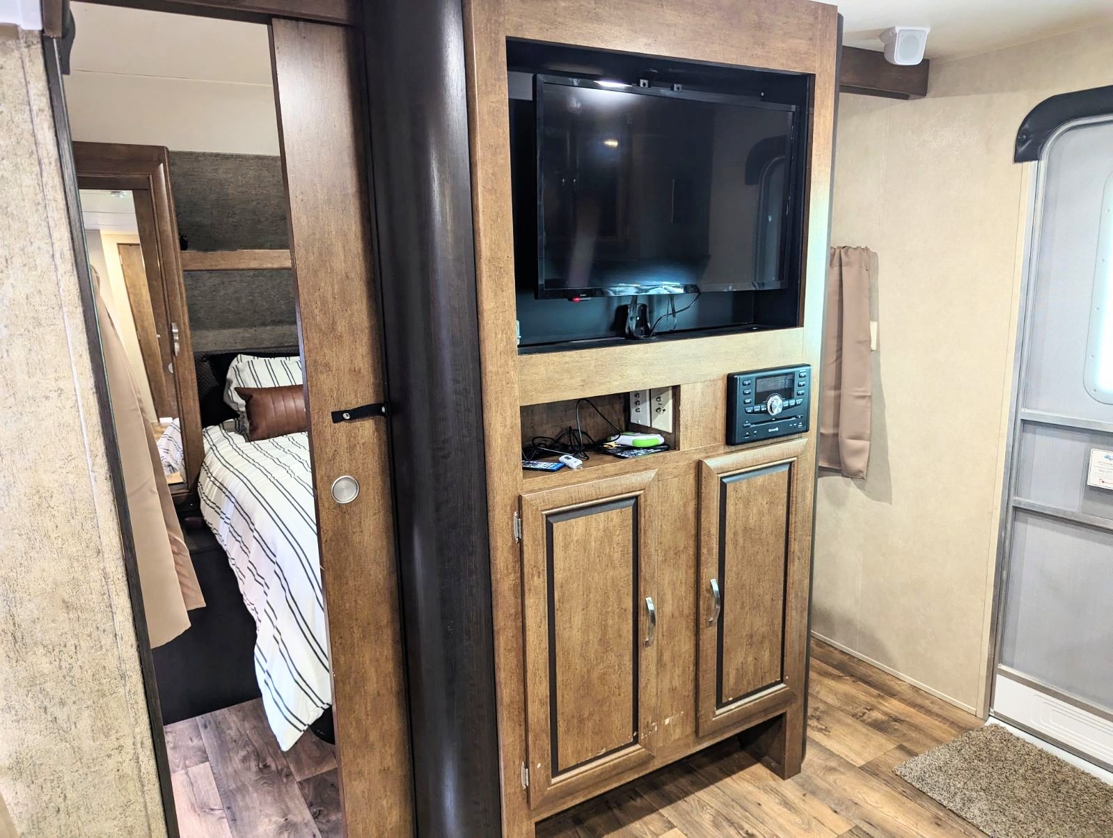 Inside an RV rental: entertainment center with TV, stereo, and bedroom reflected in a mirrored door near the entry.. Forest River Salem 2017