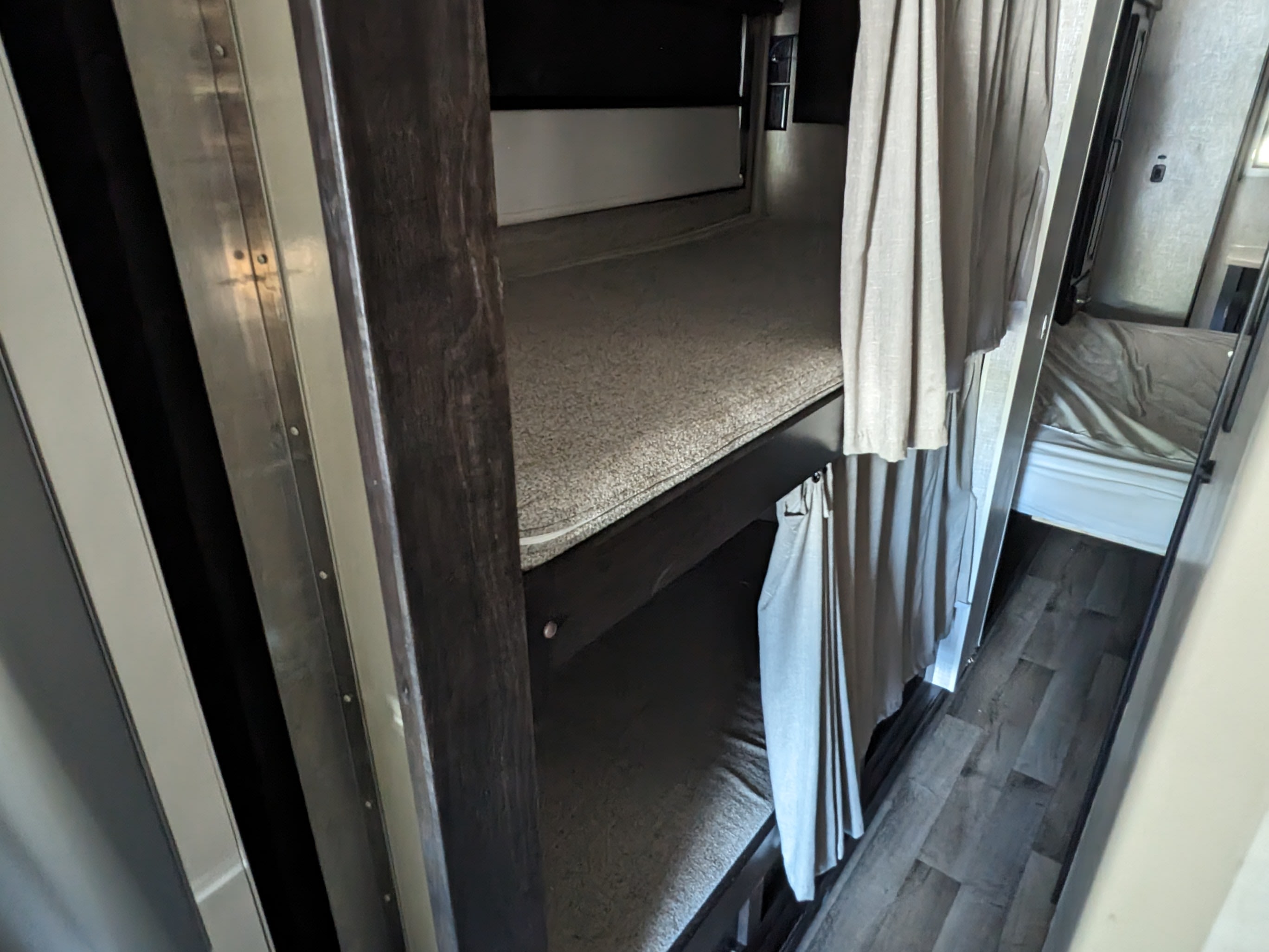 RV rental bunk beds with privacy curtains visible in a cozy interior. Ideal for extra sleeping space.. Entegra Coach Vision XL 2022