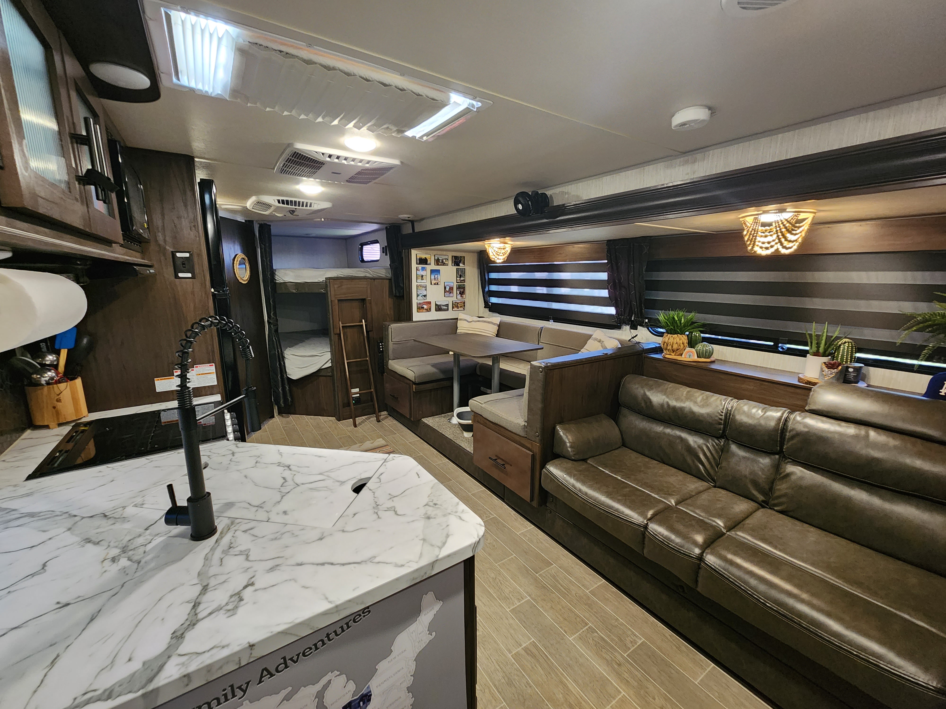 Spacious RV rental interior featuring a modern kitchen, comfortable living area with a sofa, and bunk beds. Ideal for family adventures.. Forest River Cherokee Grey Wolf Special Edition 2021