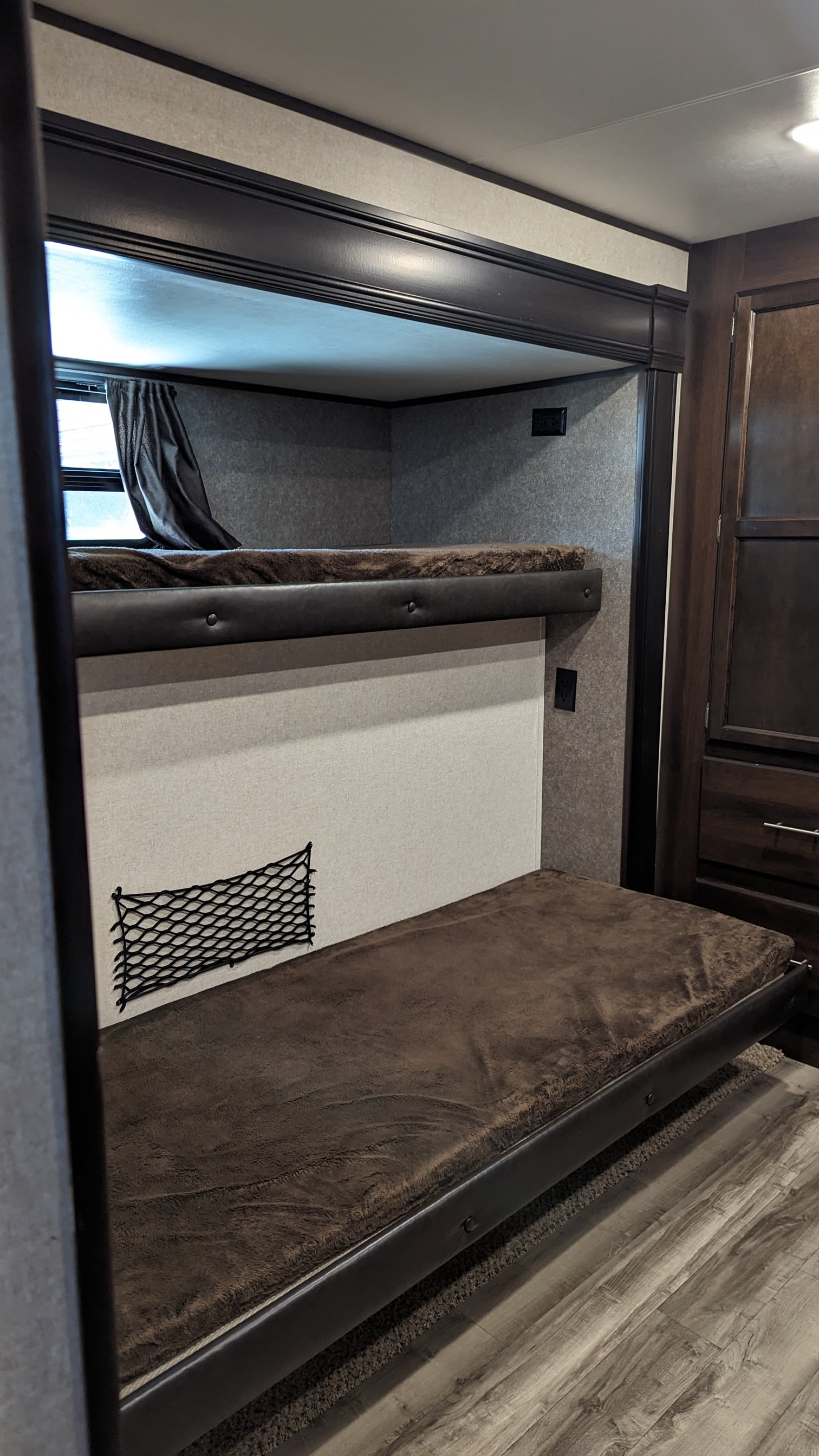 RV rental bunk beds with soft brown bedding, a window, power outlets, and a storage net for compact comfort.. Jayco Jay Flight 2019