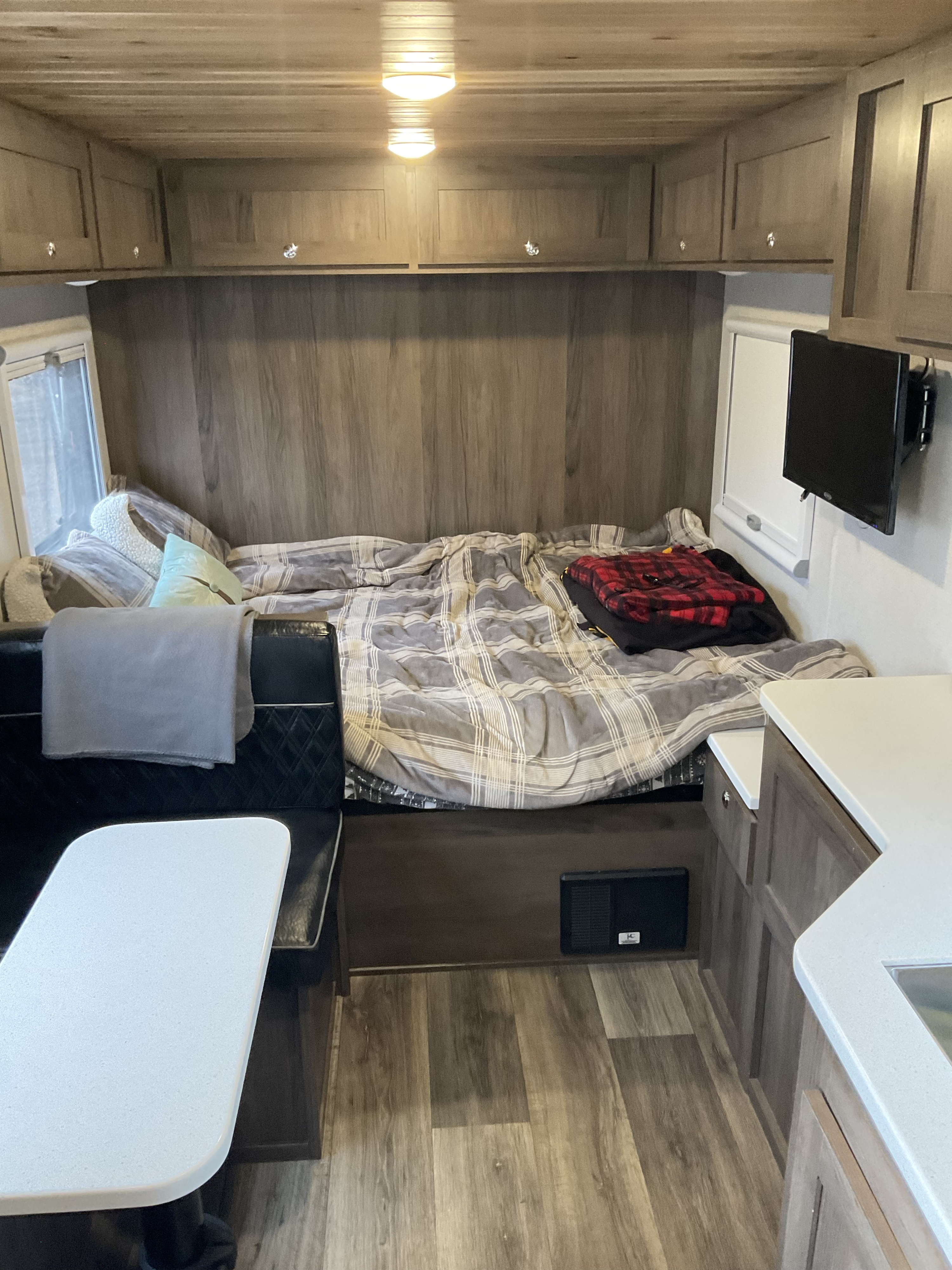 Spacious RV rental interior featuring a bed, dinette, mounted TV, and overhead storage cabinets.. Xplorer X22 2022