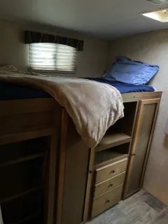 Cozy RV rental bedroom with elevated bed and ample built-in storage, ideal for compact living on the road.. Cruiser RV Shadow Cruiser 2015