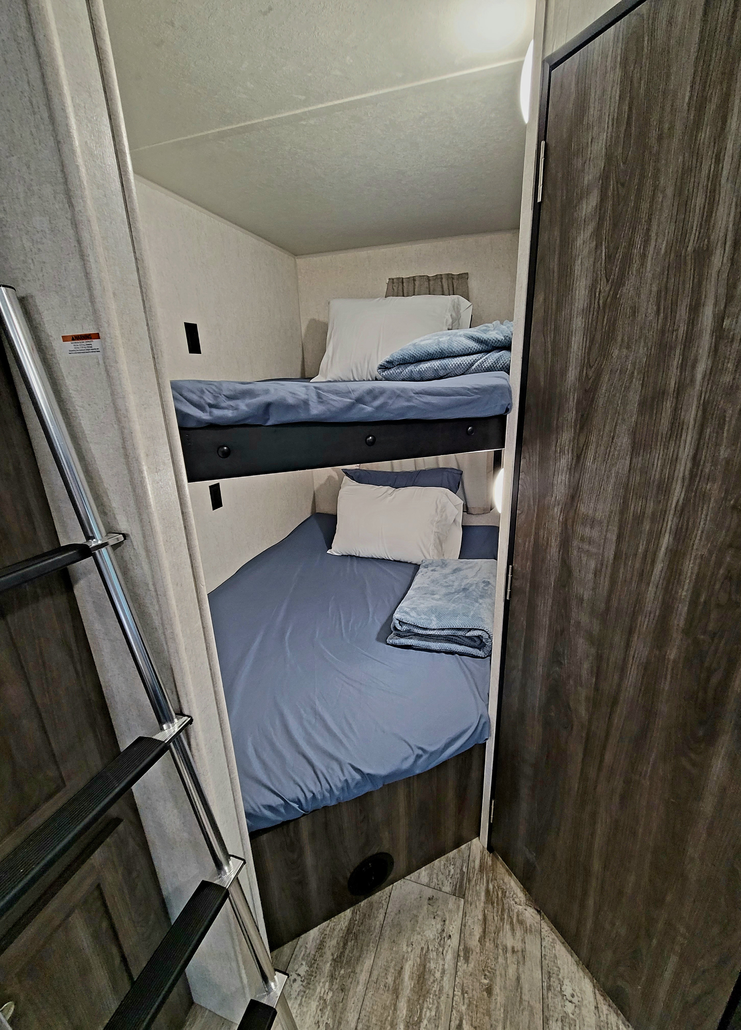 Cozy bunk beds with blue bedding and a ladder in an RV rental, ideal for family travel adventures.. Highland Ridge RV Open Range Conventional OT26BHS 2019