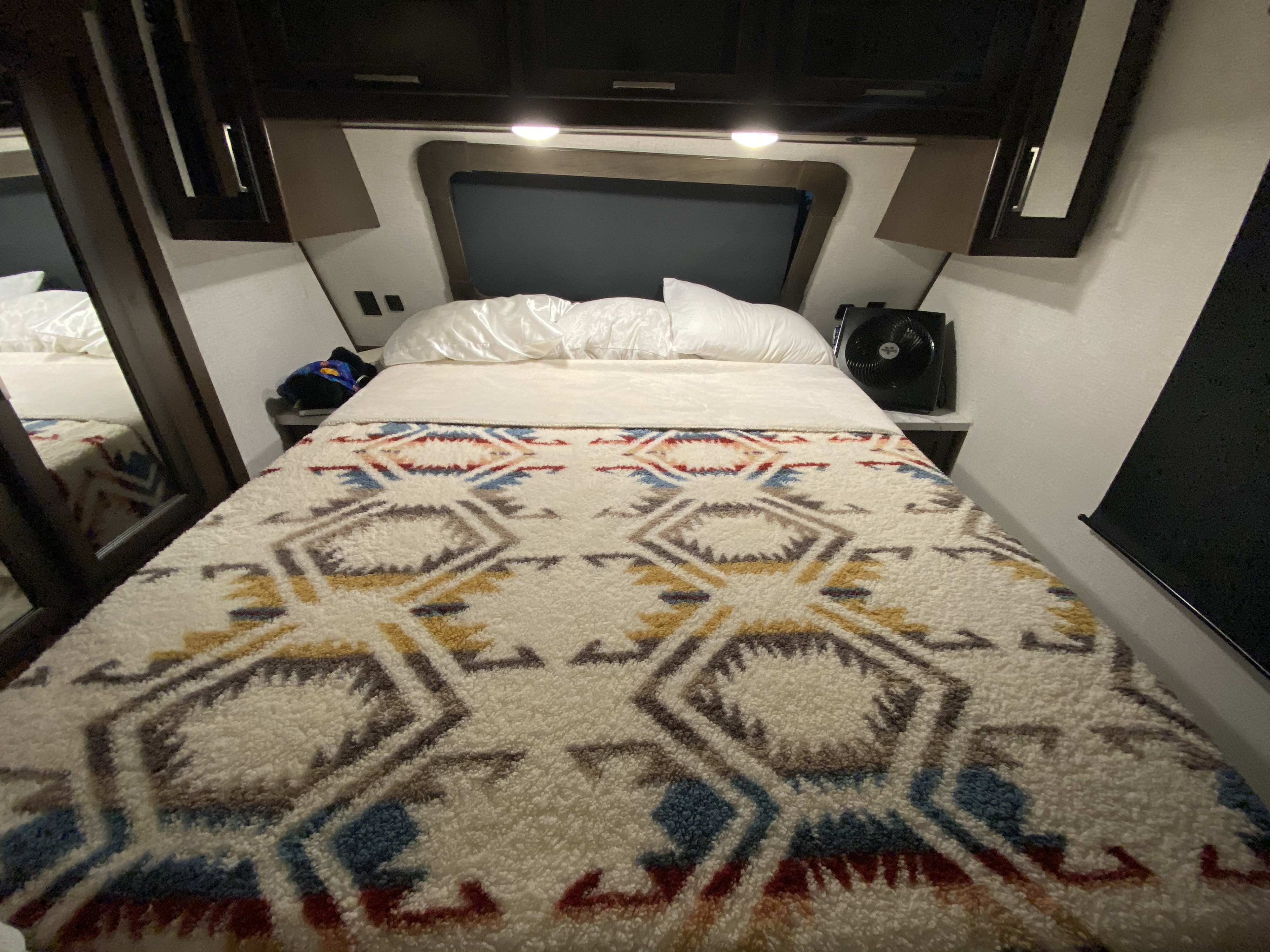 Cozy RV rental bedroom interior with a patterned blanket on the bed, overhead storage, and a small fan.. Atlas Atlas Fifth Wheel 2020