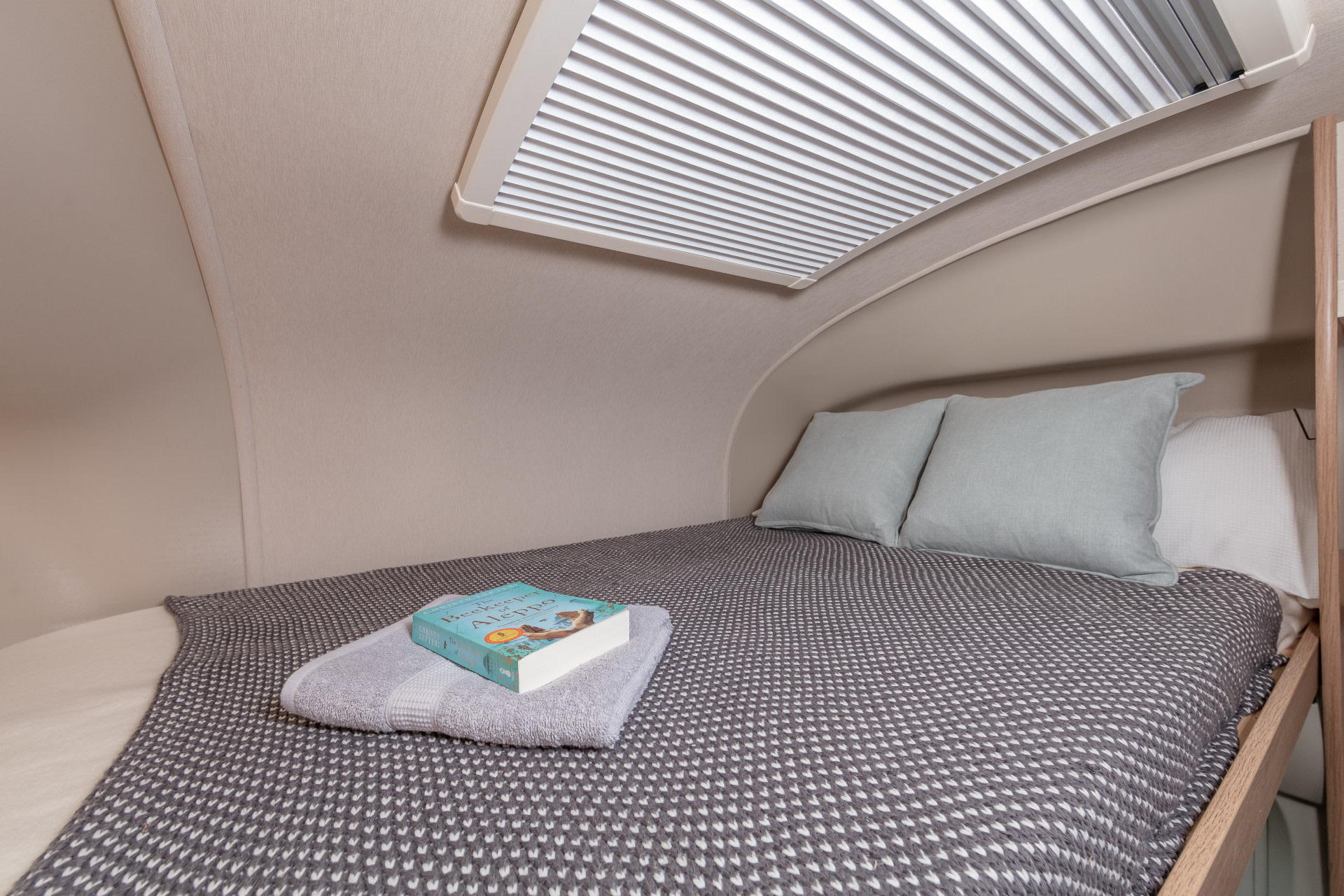 Compact RV rental sleeping area with a comfortable bed, light pillows, and a large roof skylight for natural light.. Auto-Trail Imala 736 2024