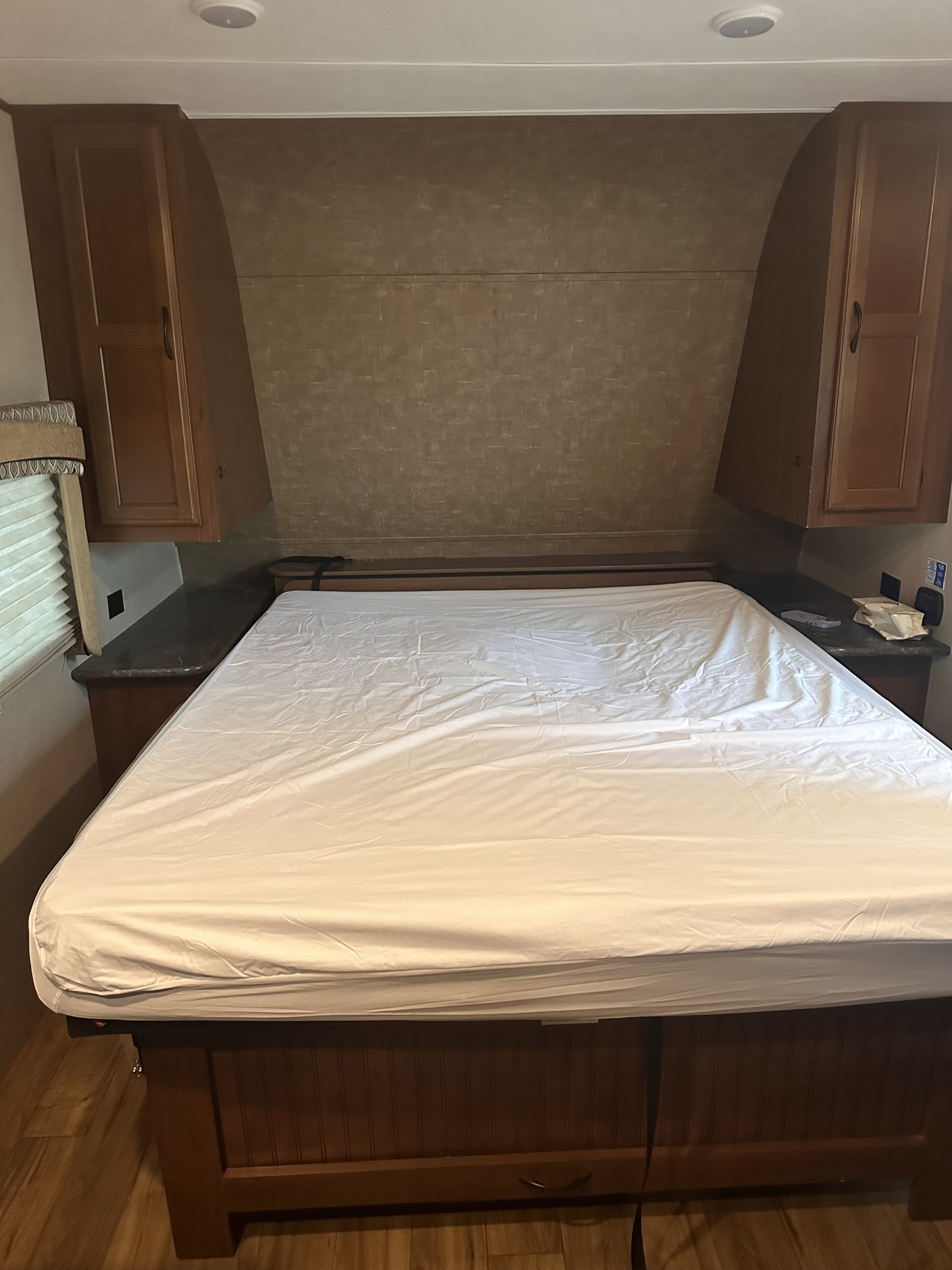 Inviting RV rental bedroom showing a bed with white sheets, wood cabinets, and built-in nightstands.. Jayco Jay Flight 2017