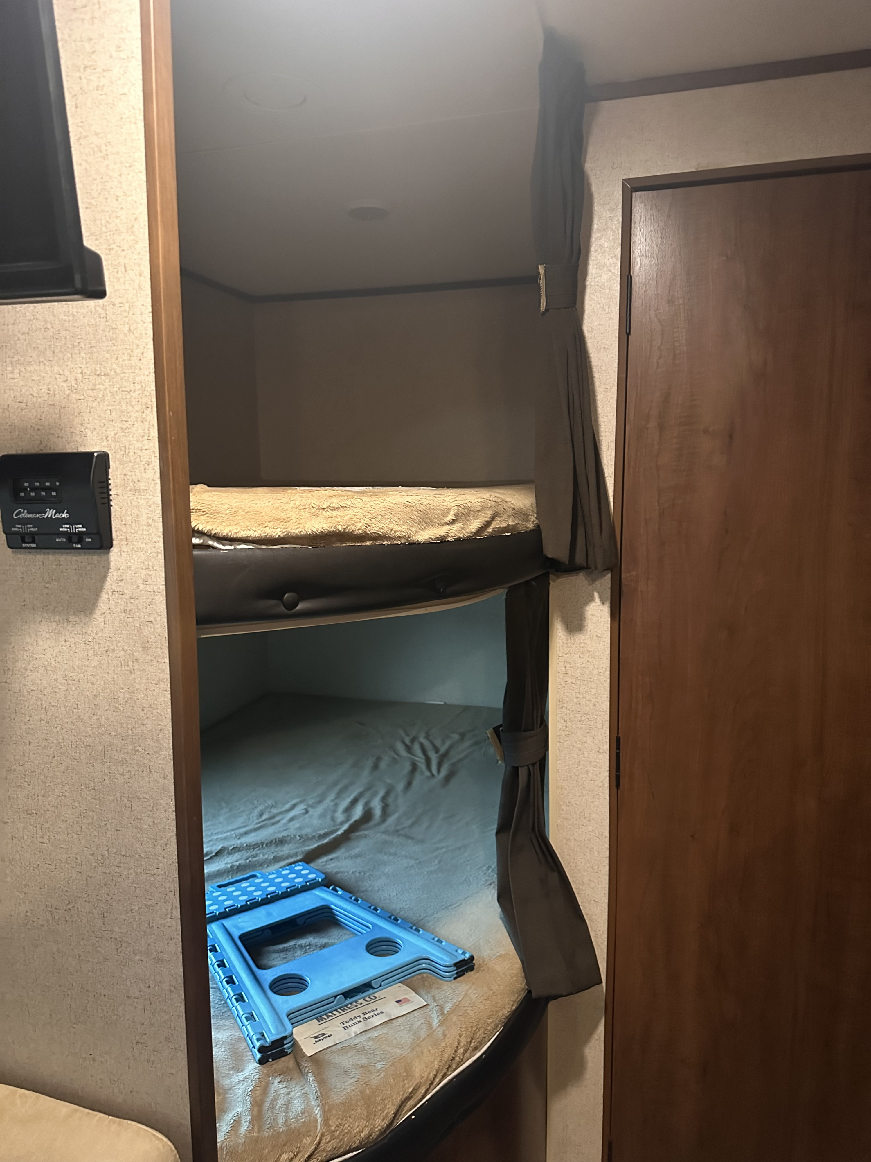 This RV rental interior features compact bunk beds, perfect for family adventures. A step stool and thermostat are visible.. Jayco Jay Flight 2017