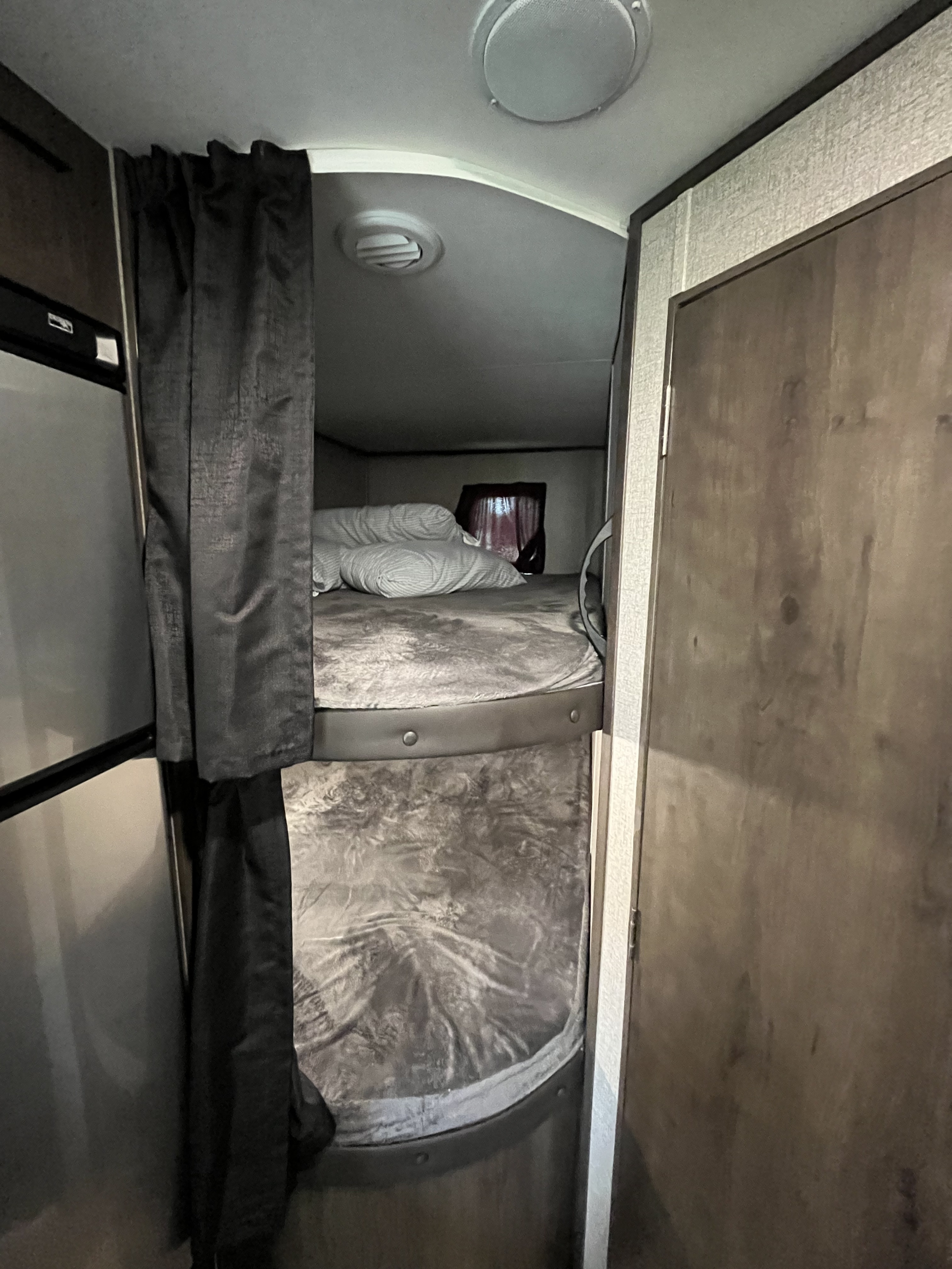 RV rental interior showing comfortable bunk beds with privacy curtains and adjacent fridge.. Jayco Jay Flight SLX 2021