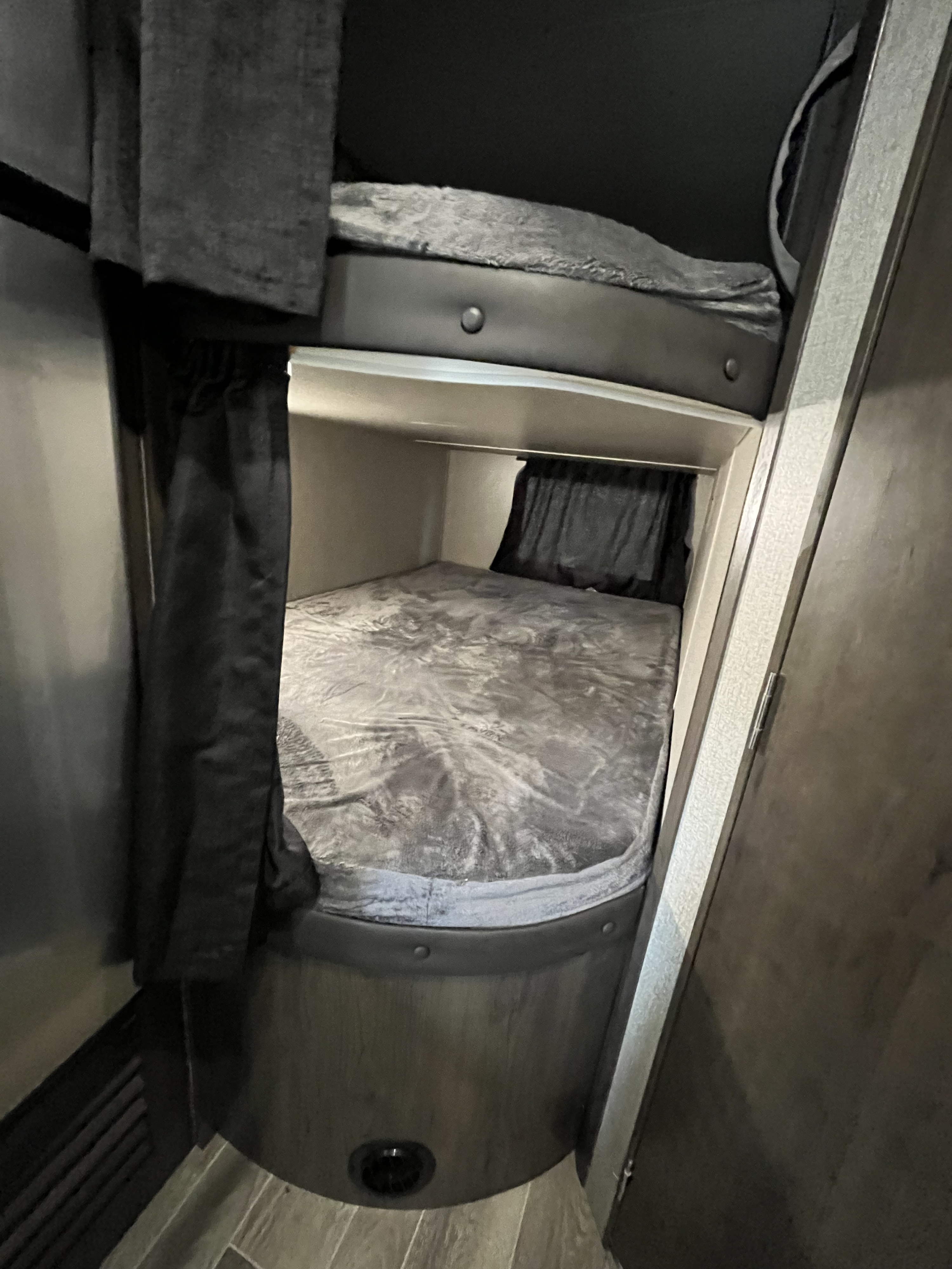 RV rental bunk beds. Compact interior features two stacked bunks with grey bedding and dark privacy curtains for a cozy sleep space.. Jayco Jay Flight SLX 2021