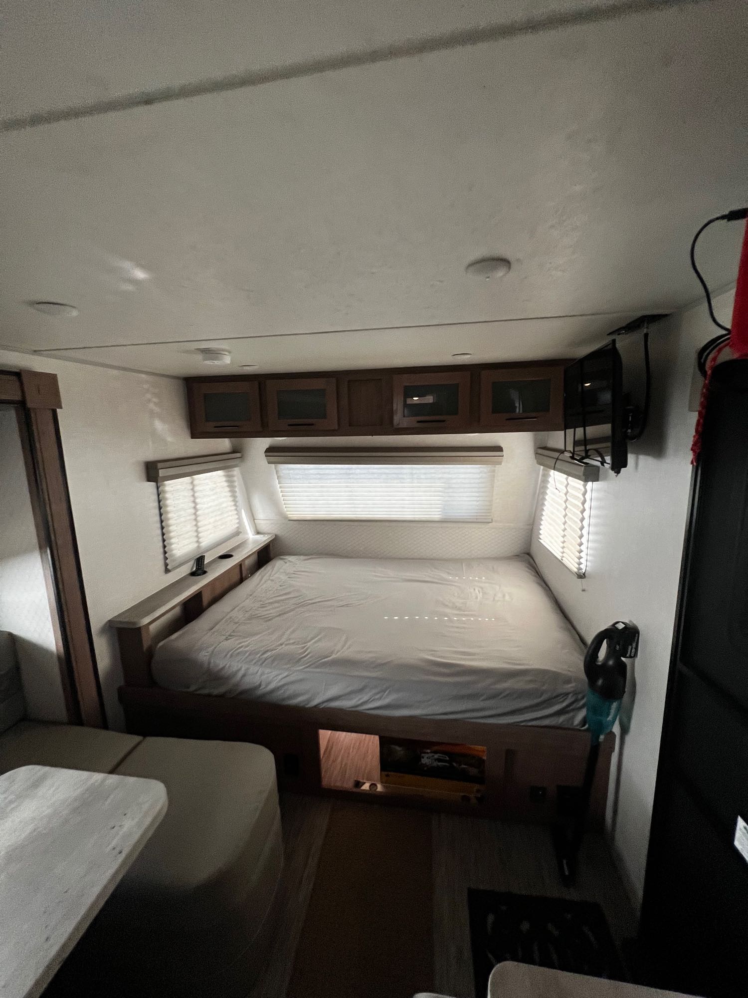 RV rental bedroom: A bright, compact interior showing a large bed, windows with blinds, and overhead storage cabinets.. No Boundaries 19 2020