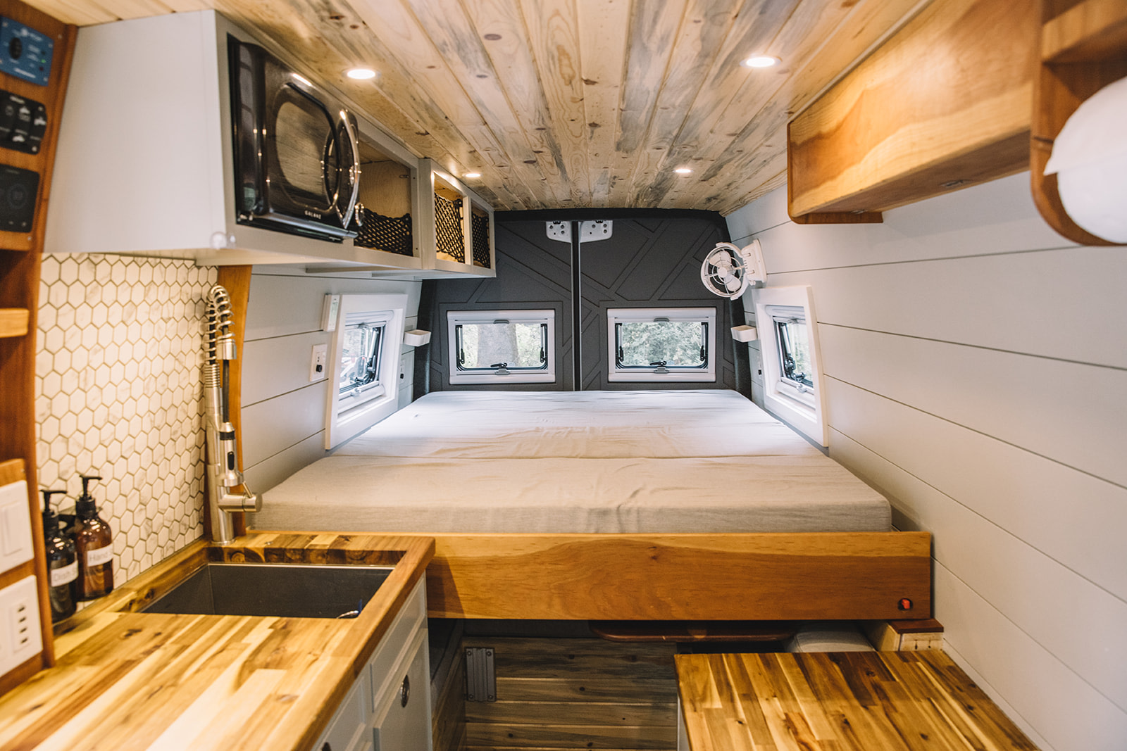 RV rental interior: A cozy camper van with a spacious bed, modern kitchen, and wooden accents throughout.. Mercedes Sprinter 2019