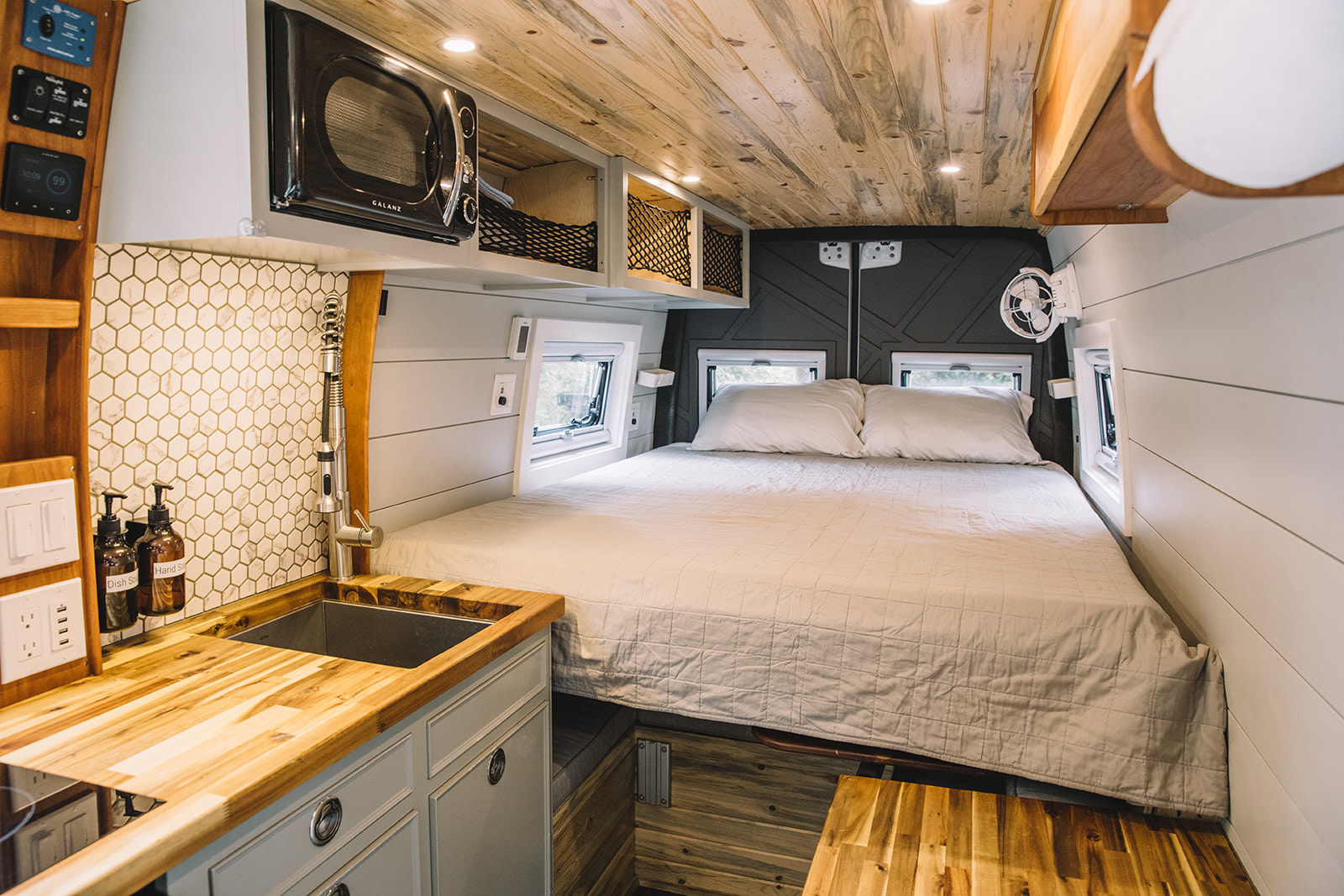 Cozy RV rental interior featuring a built-in bed, fully equipped kitchenette, and warm wood accents.. Mercedes Sprinter 2019