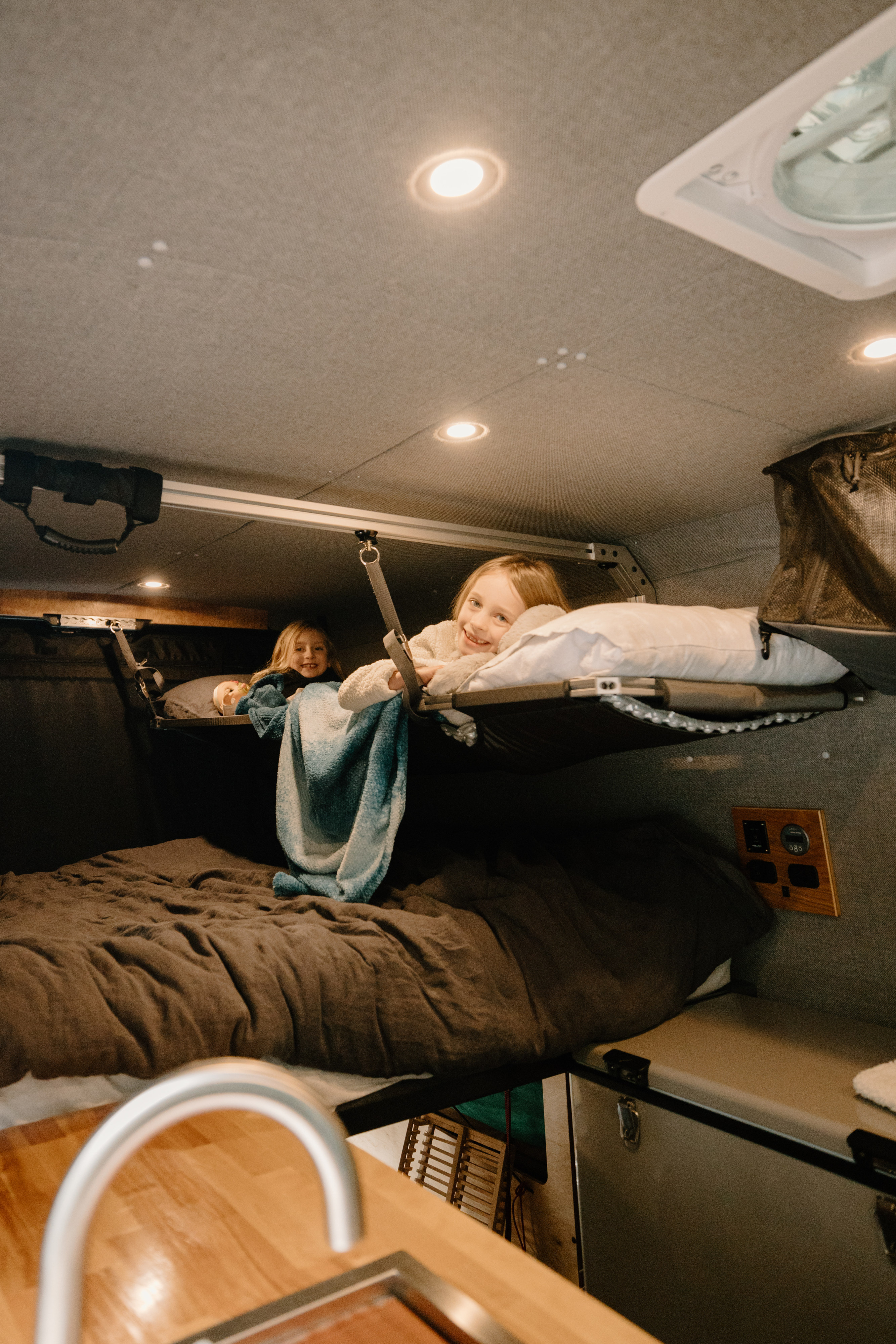 Cozy RV rental interior shows two smiling girls in bunk beds, enjoying family van life adventures.. Dodge Ram Promaster 2500 2020