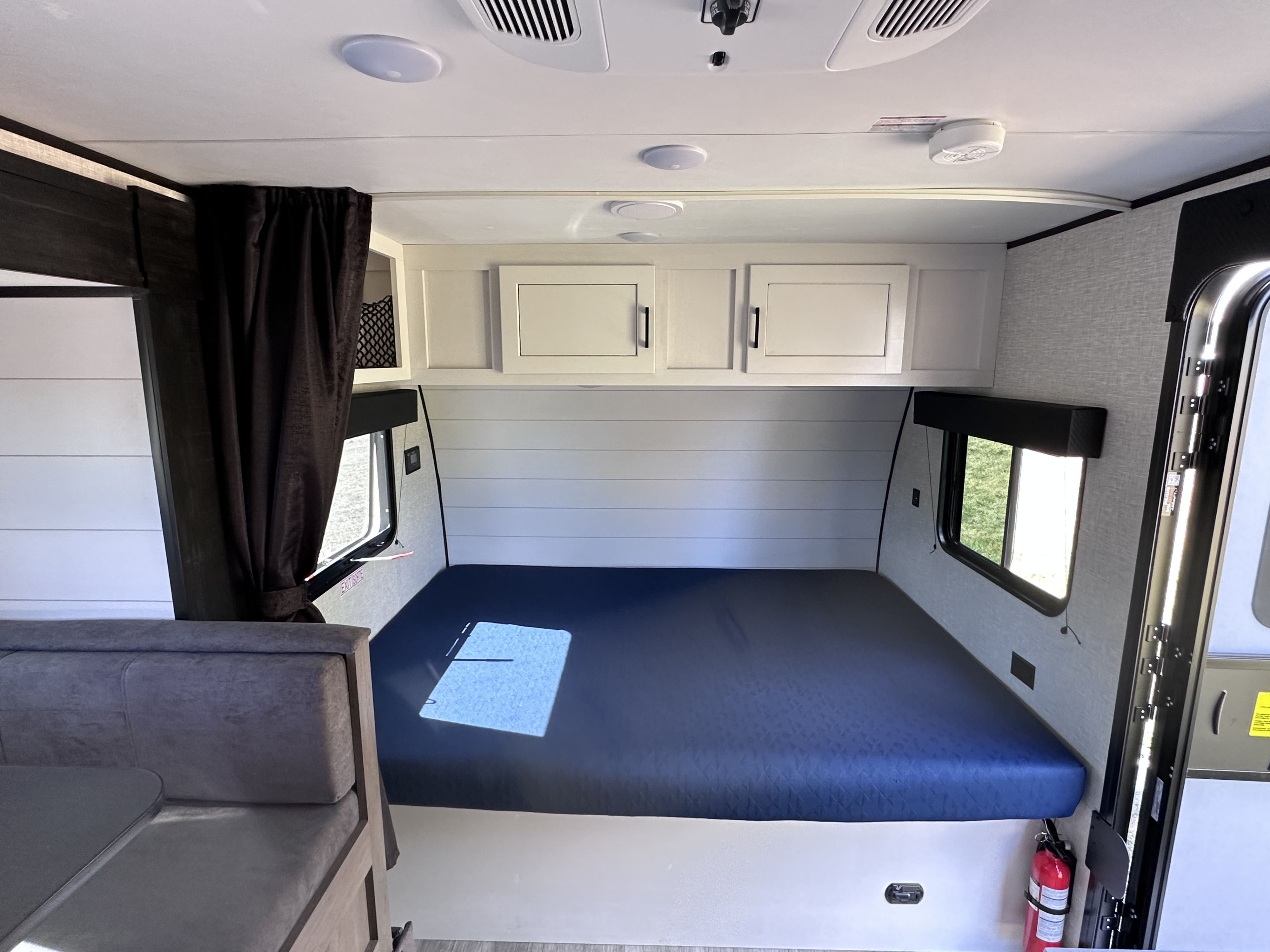 Clean and modern RV rental interior featuring a comfortable bed, overhead cabinets, and a cozy dinette area.. Jayco Jay Flight SLX Baja Edition 2024