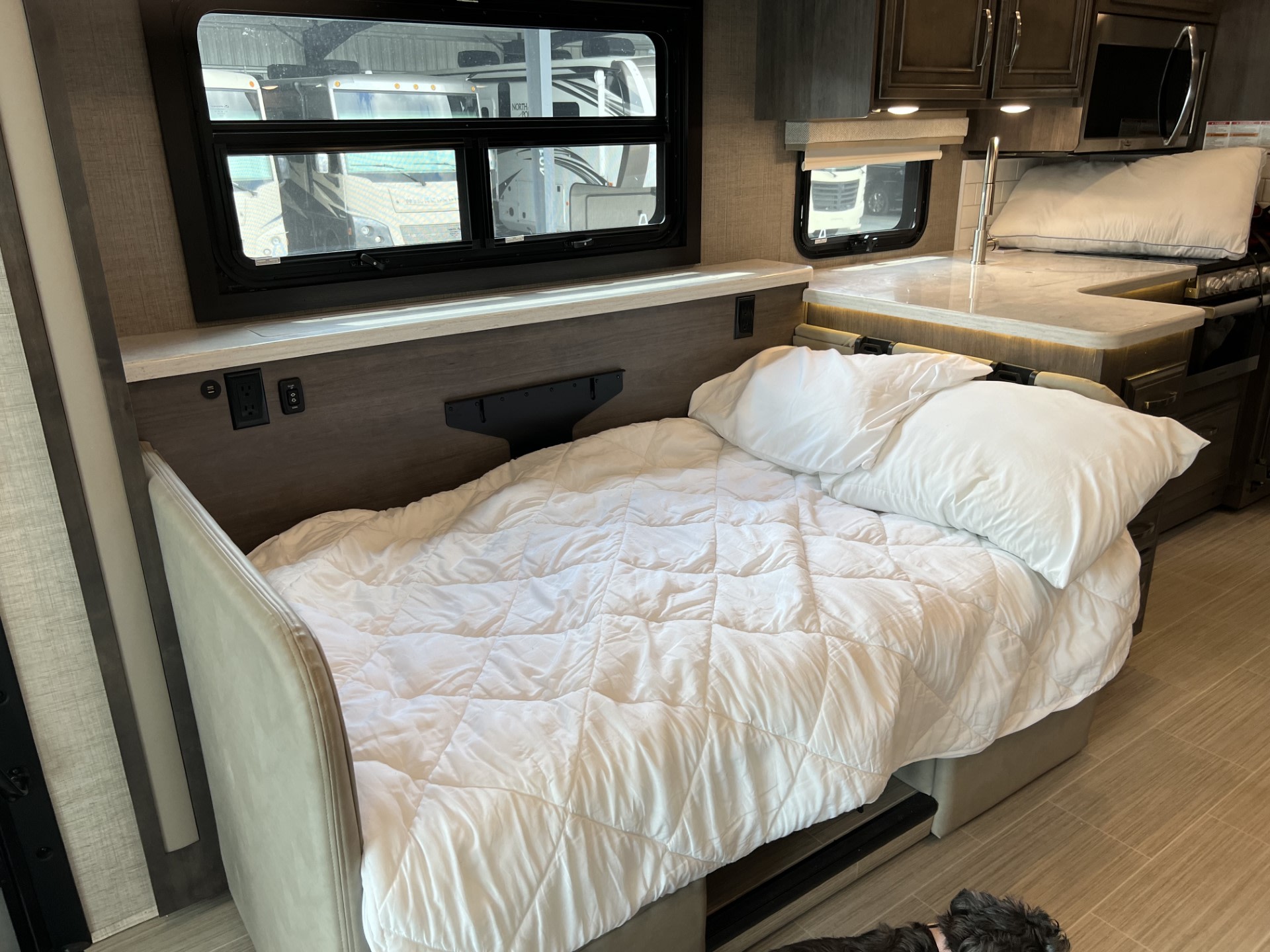 Spacious rv rental interior: A cozy bed with white linens, functional kitchen, and bright windows for travel.. Entegra Coach Vision XL 2023
