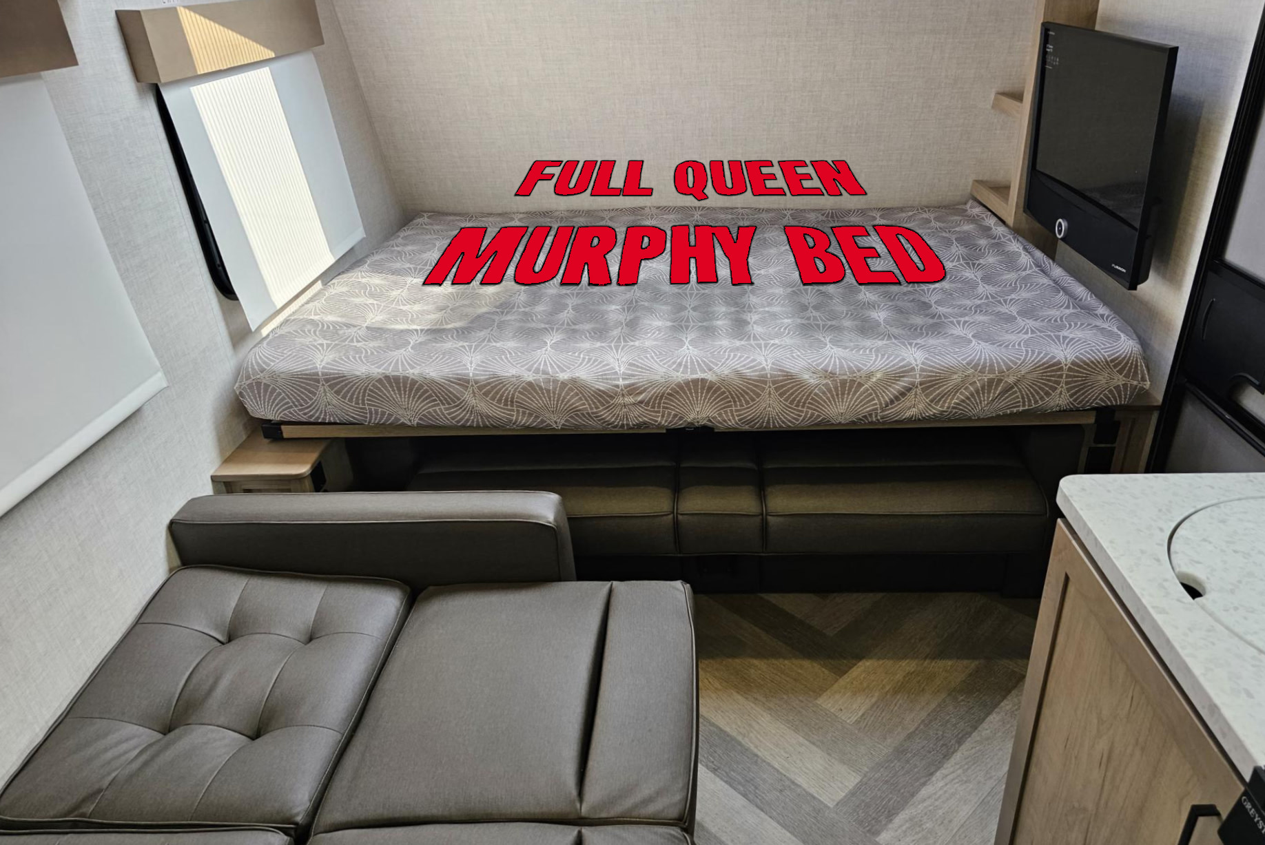 RV rental interior featuring a full queen Murphy bed folded down over a cozy sofa, maximizing space for travel.. Ember Overland 2022