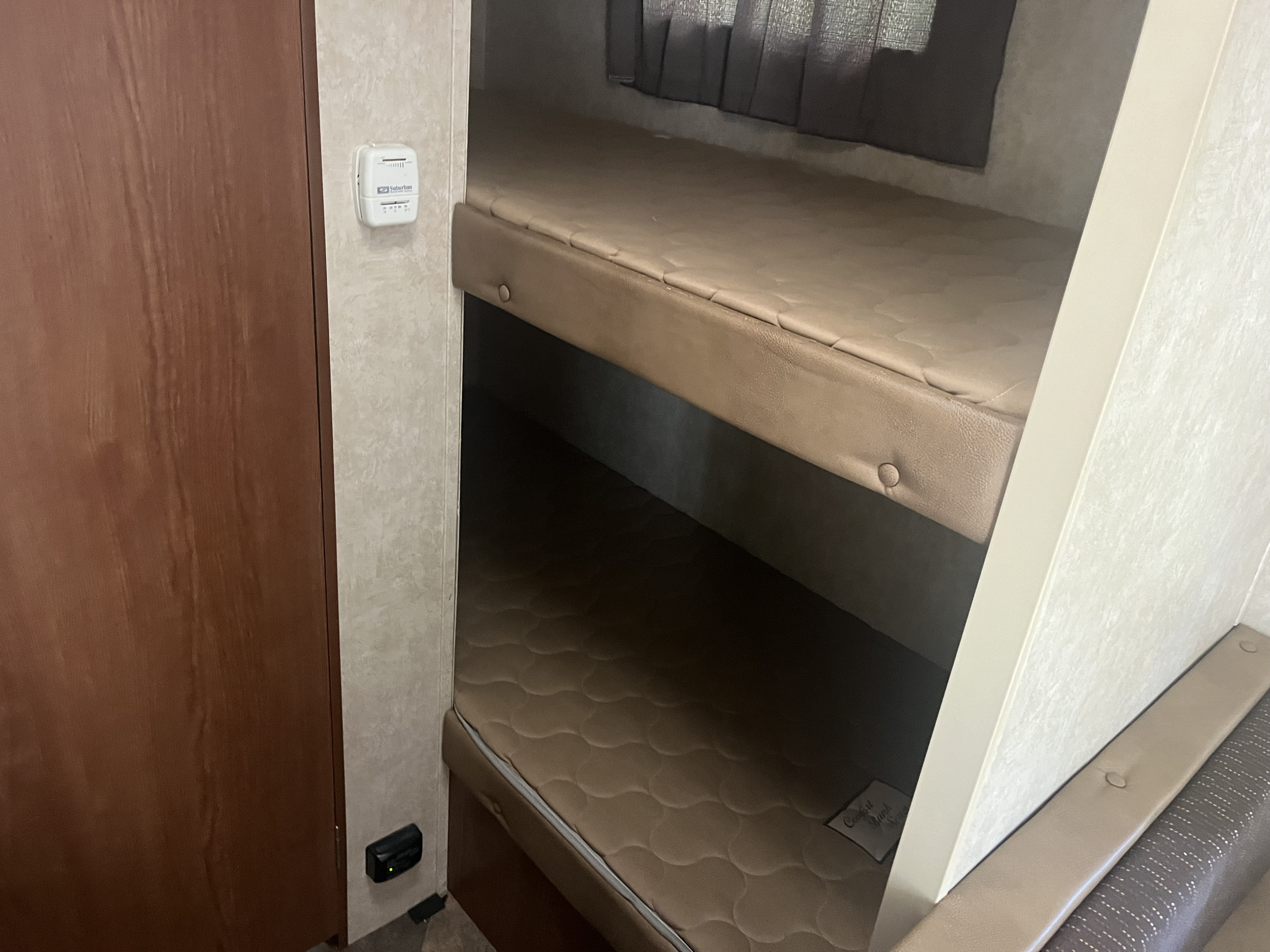 Inside this RV rental: two comfy bunk beds with a Suburban thermostat and window blinds for a cozy sleep setup.. Forest River Salem Cruise Lite 2015