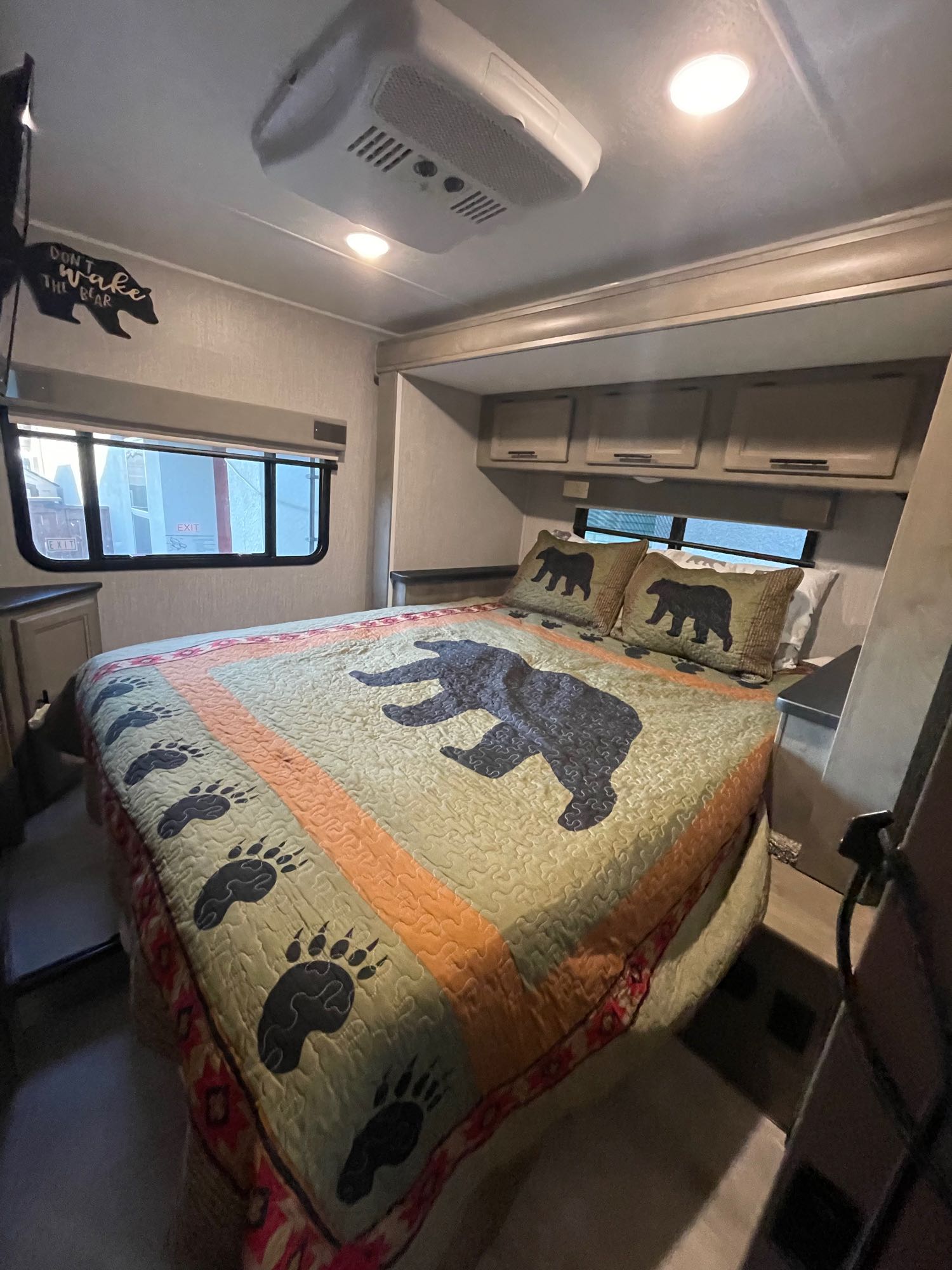Experience comfort in this RV rental bedroom: bear-themed quilt, pillows, and decor create a cozy, well-appointed space.. Forest River Coachmen Freelander 2021