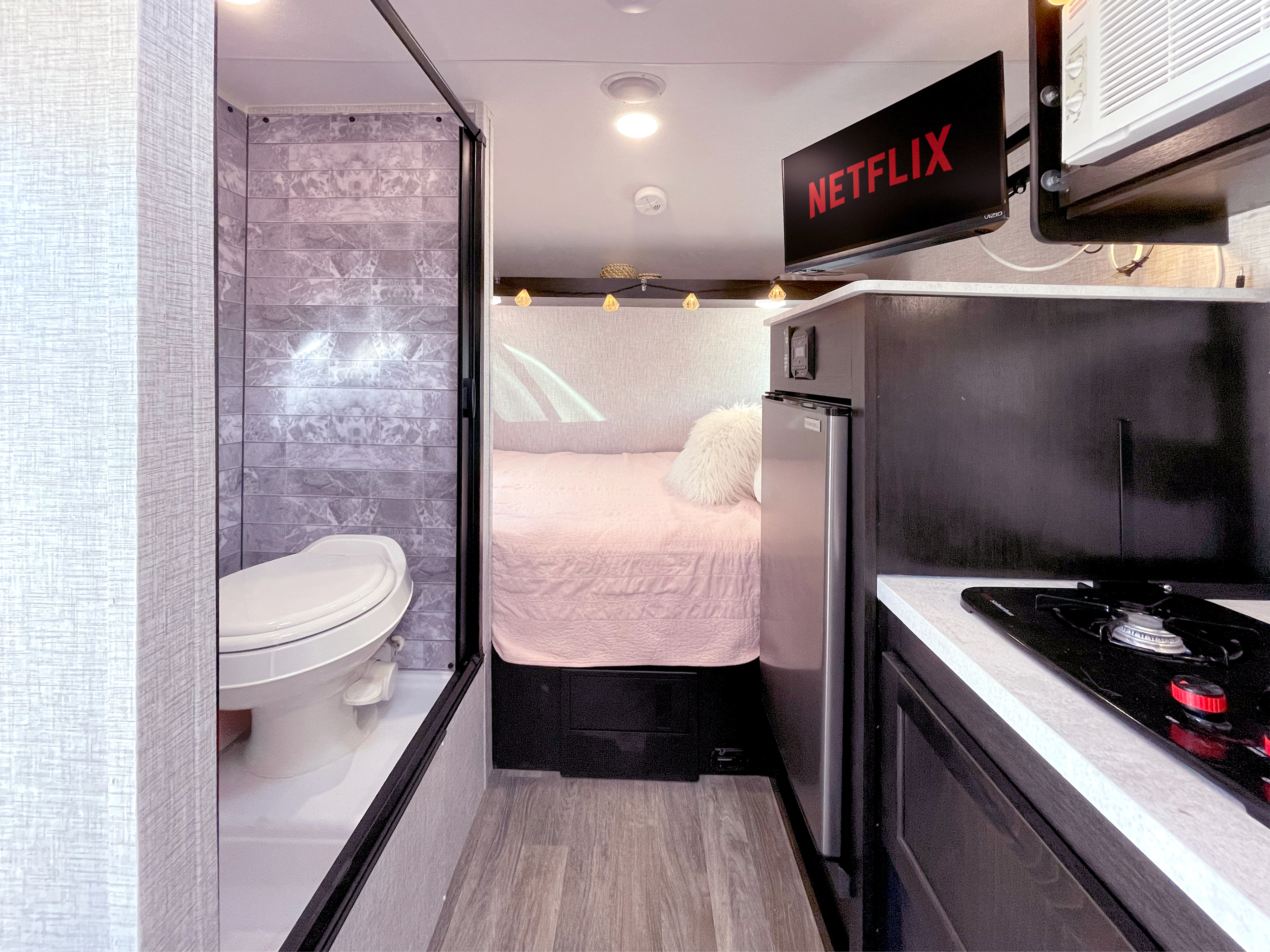 An inviting RV rental interior featuring a compact bath, cozy bedroom, kitchenette, and Netflix TV.. Braxton Creek Bushwhacker Plus 2022