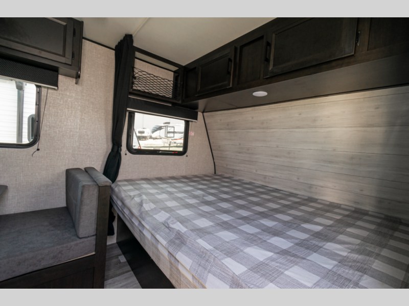 Explore the comfortable interior of this RV rental. It features a cozy bed, sleek overhead cabinets, and a seating area for your travels.. Jayco Jay Flight SLX STX Edition 2022
