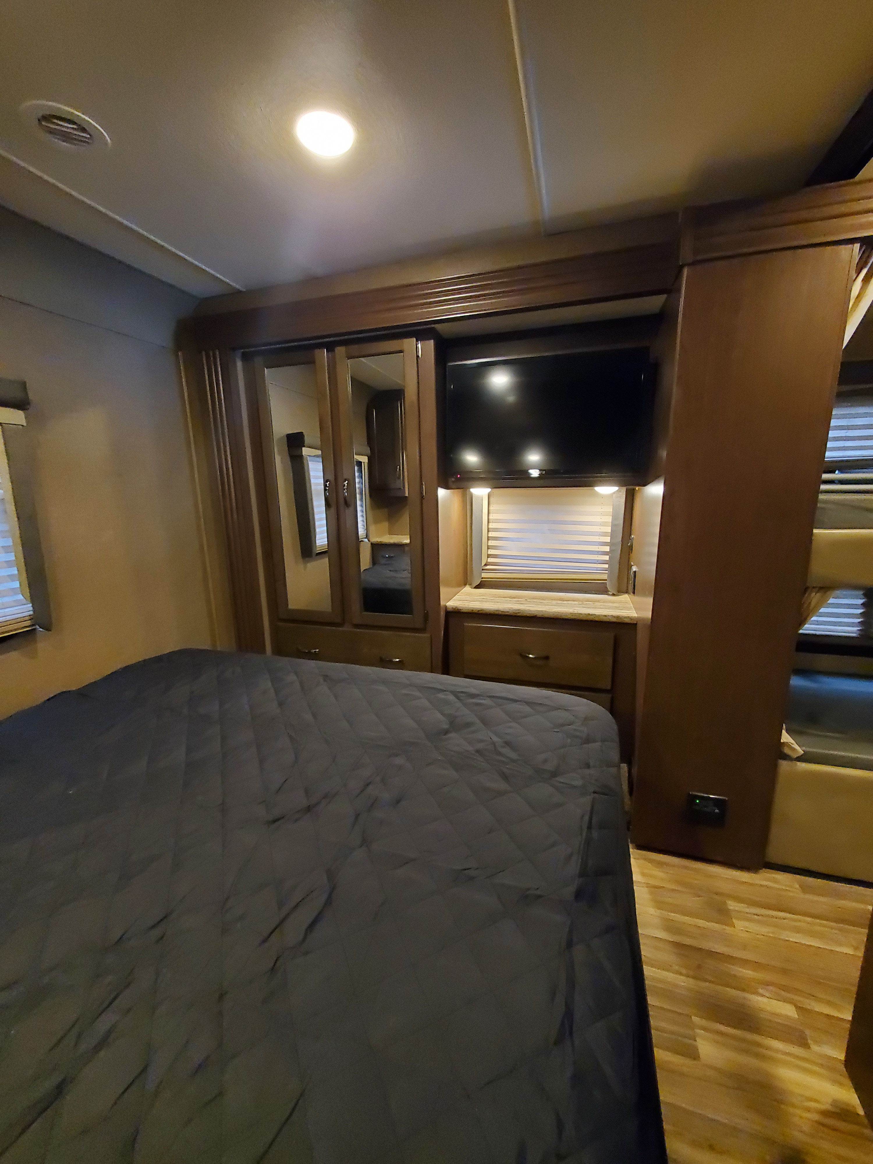 RV rental bedroom: bed, TV, mirrored closet, and compact bunk. Perfect for road trip comfort.. Thor Motor Coach A.C.E 2018