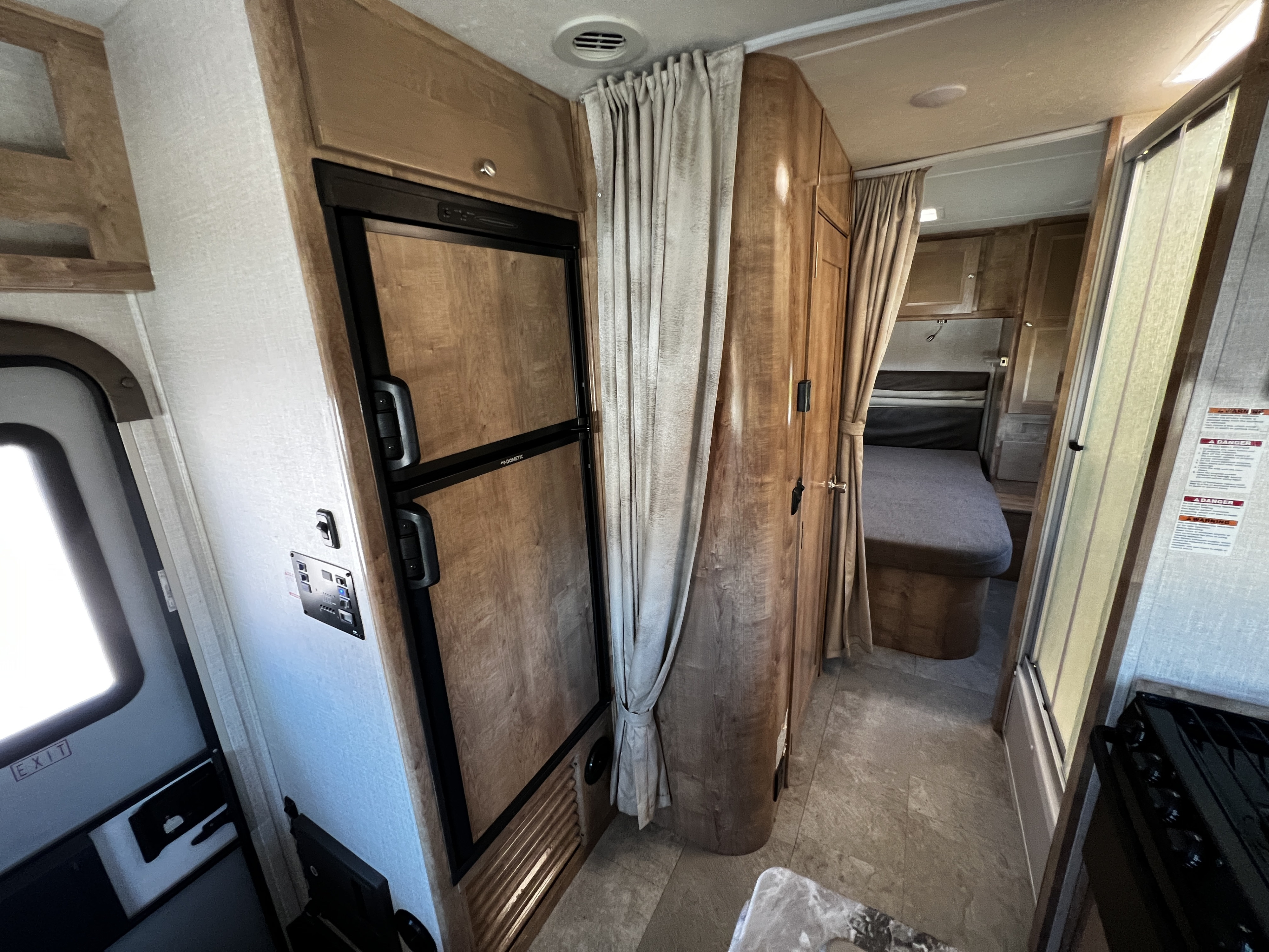 Explore this RV rental's inviting interior: sleek fridge, control panel, and comfy rear bedroom. Perfect for your next adventure.. Forest River Coachmen Leprechaun 2020